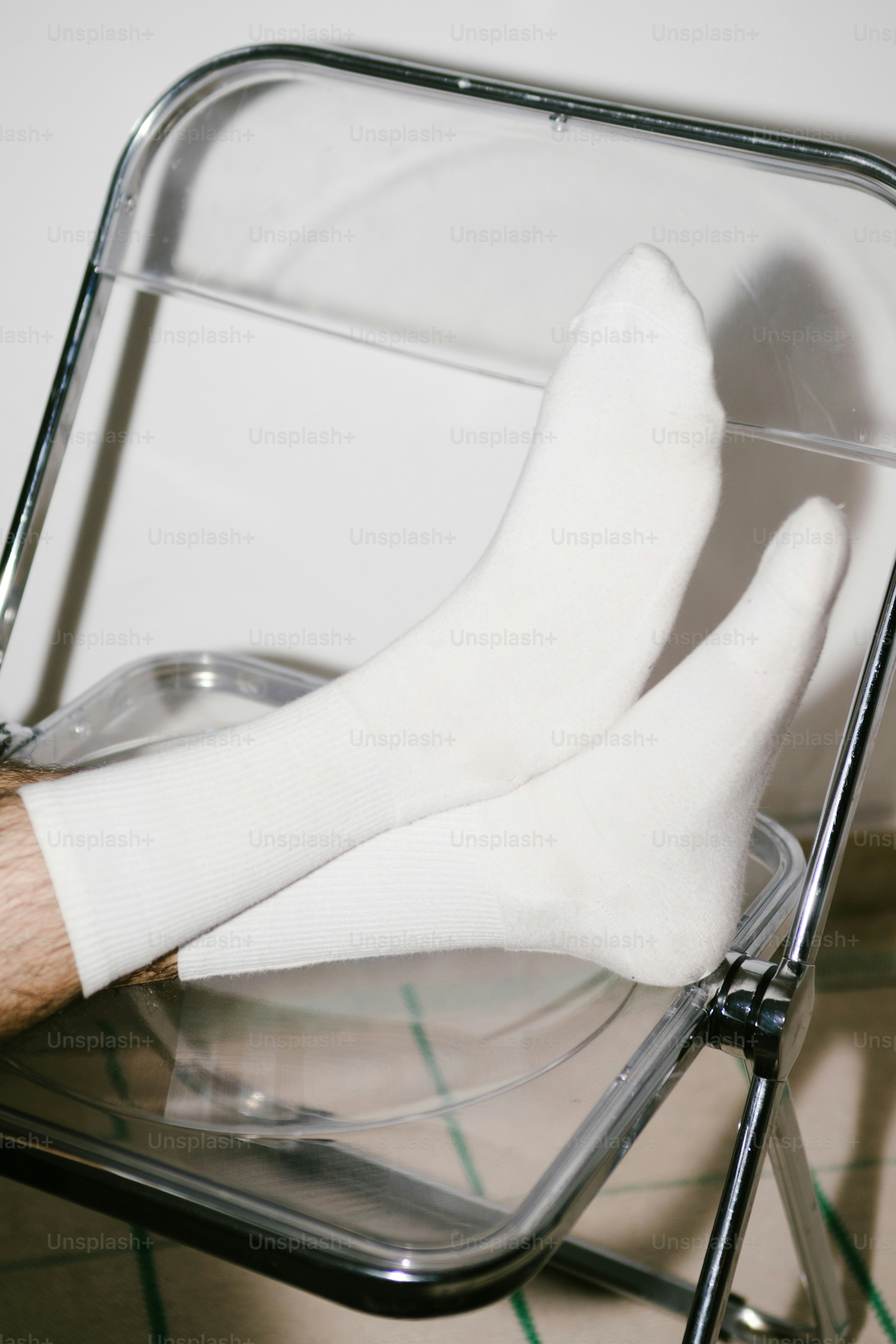 White socks on a person sitting on a clear chair