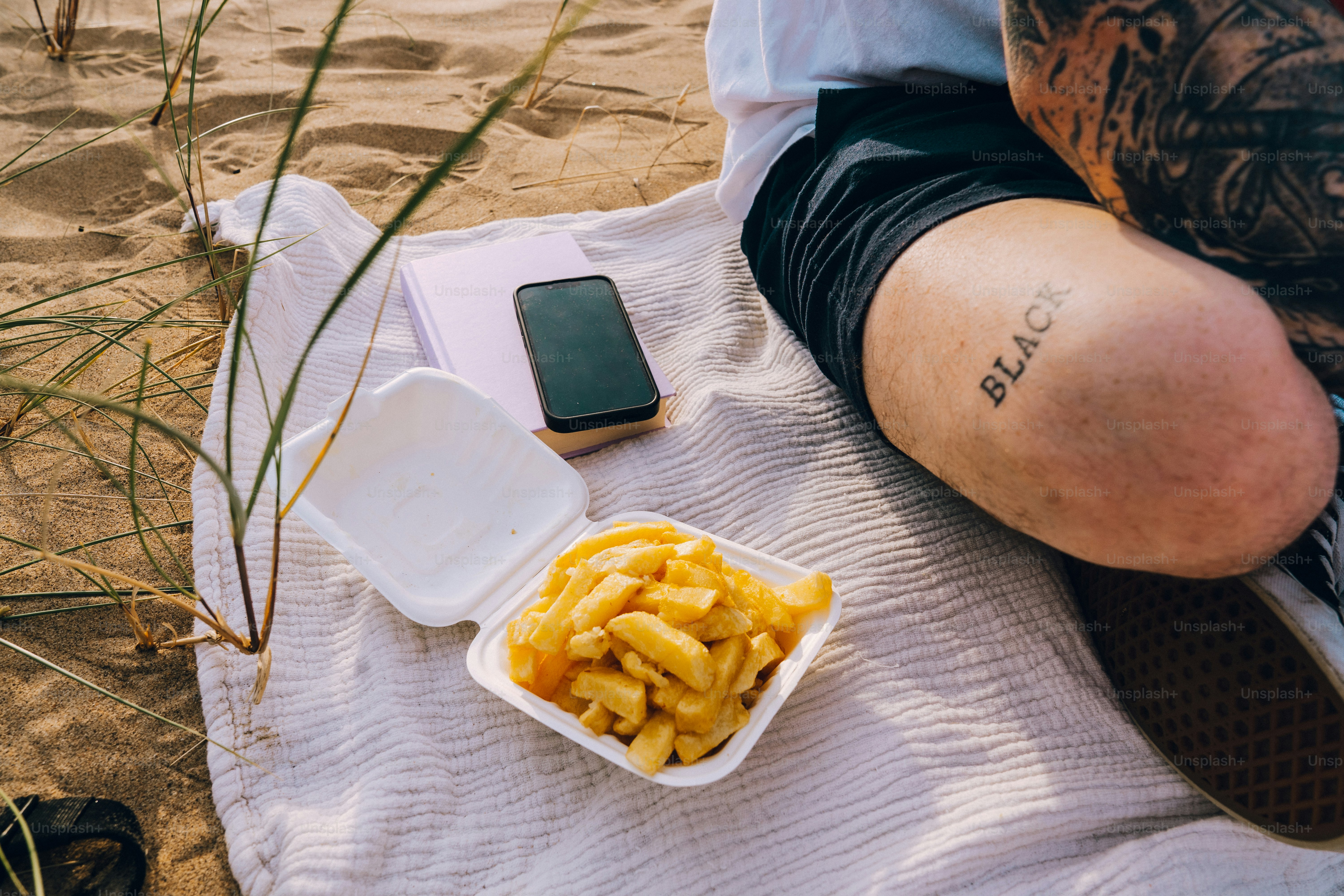 Orang dengan kentang goreng di atas selimut di pantai.