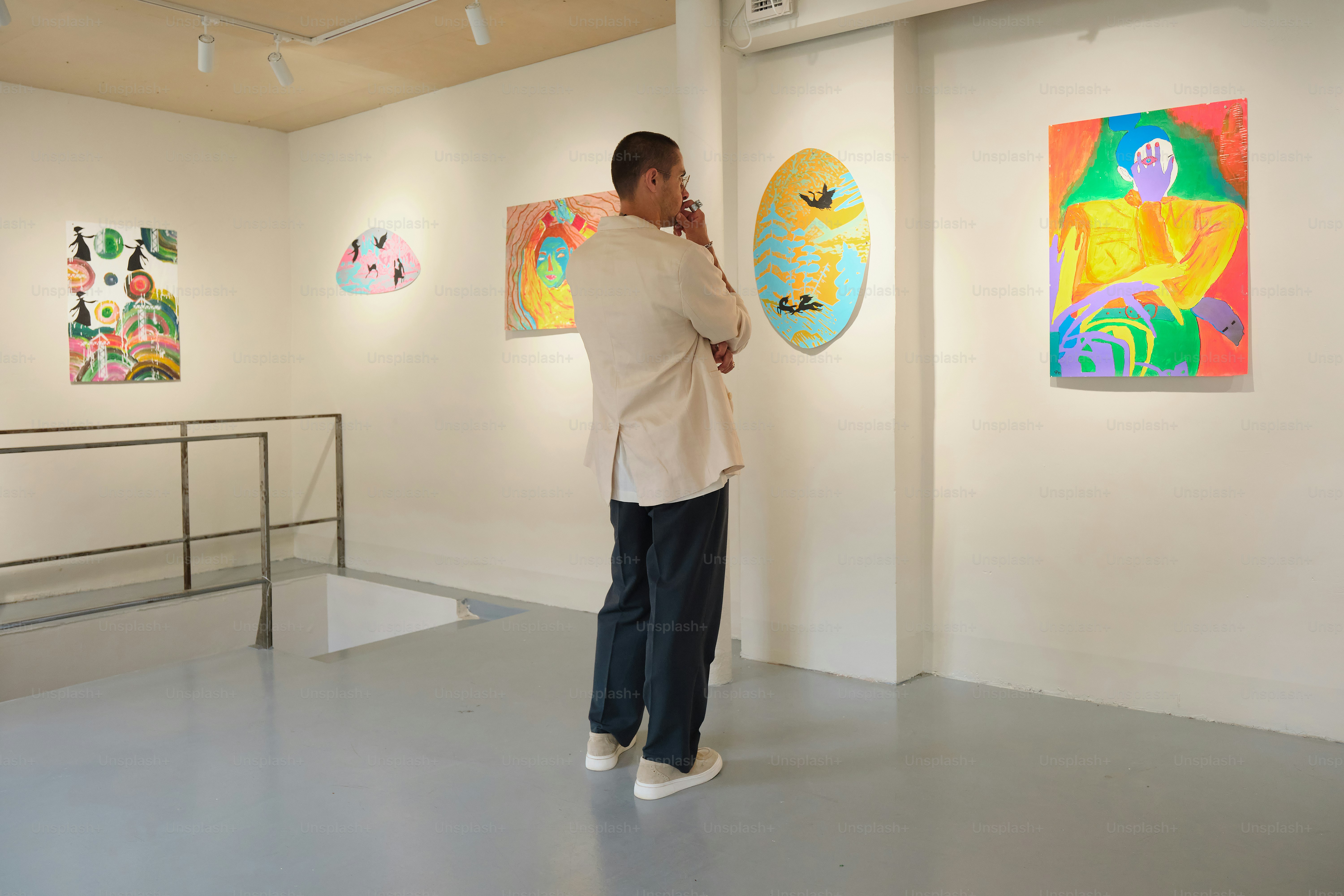 Man observing colorful abstract art in gallery.