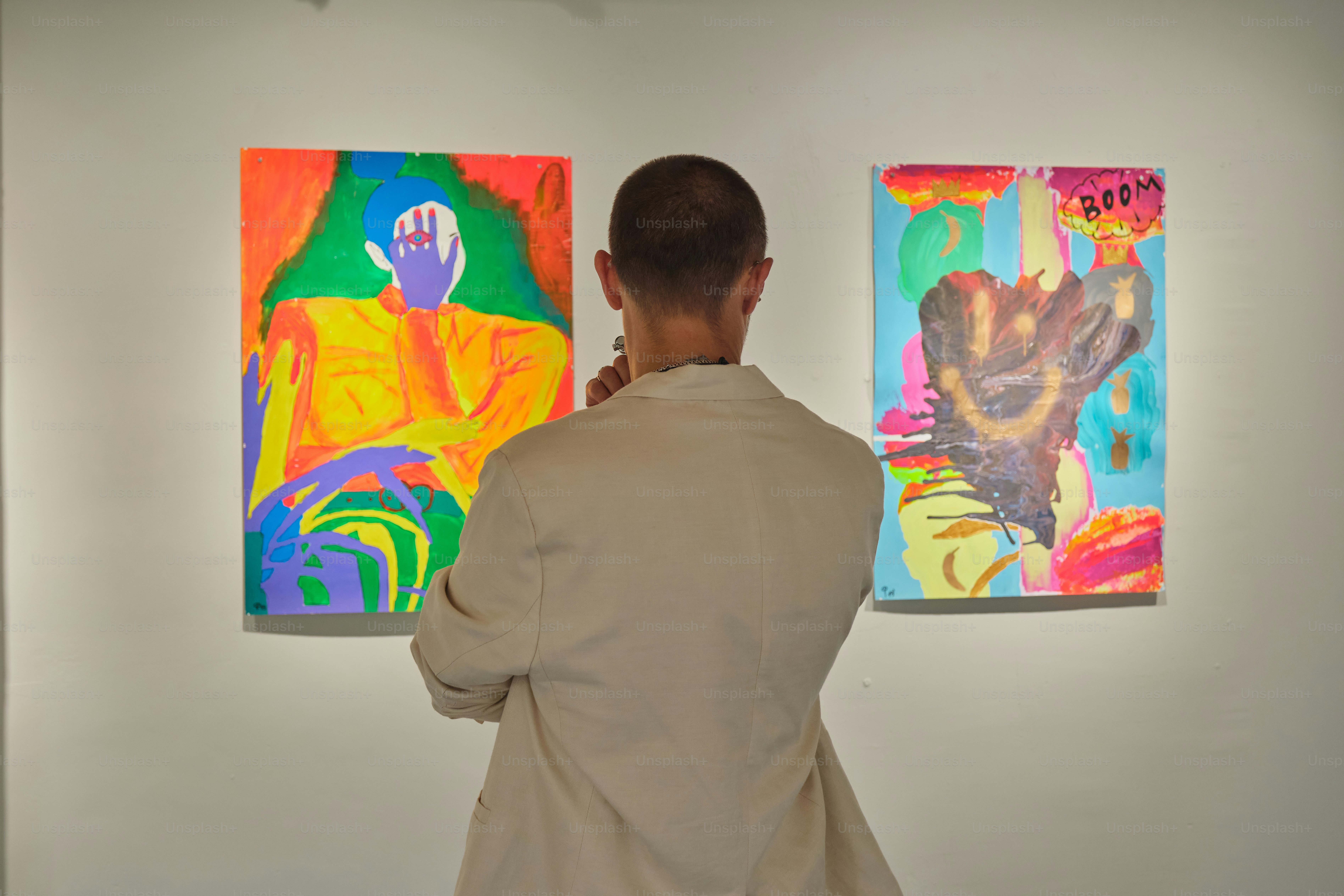 Man observing colorful abstract paintings in a gallery