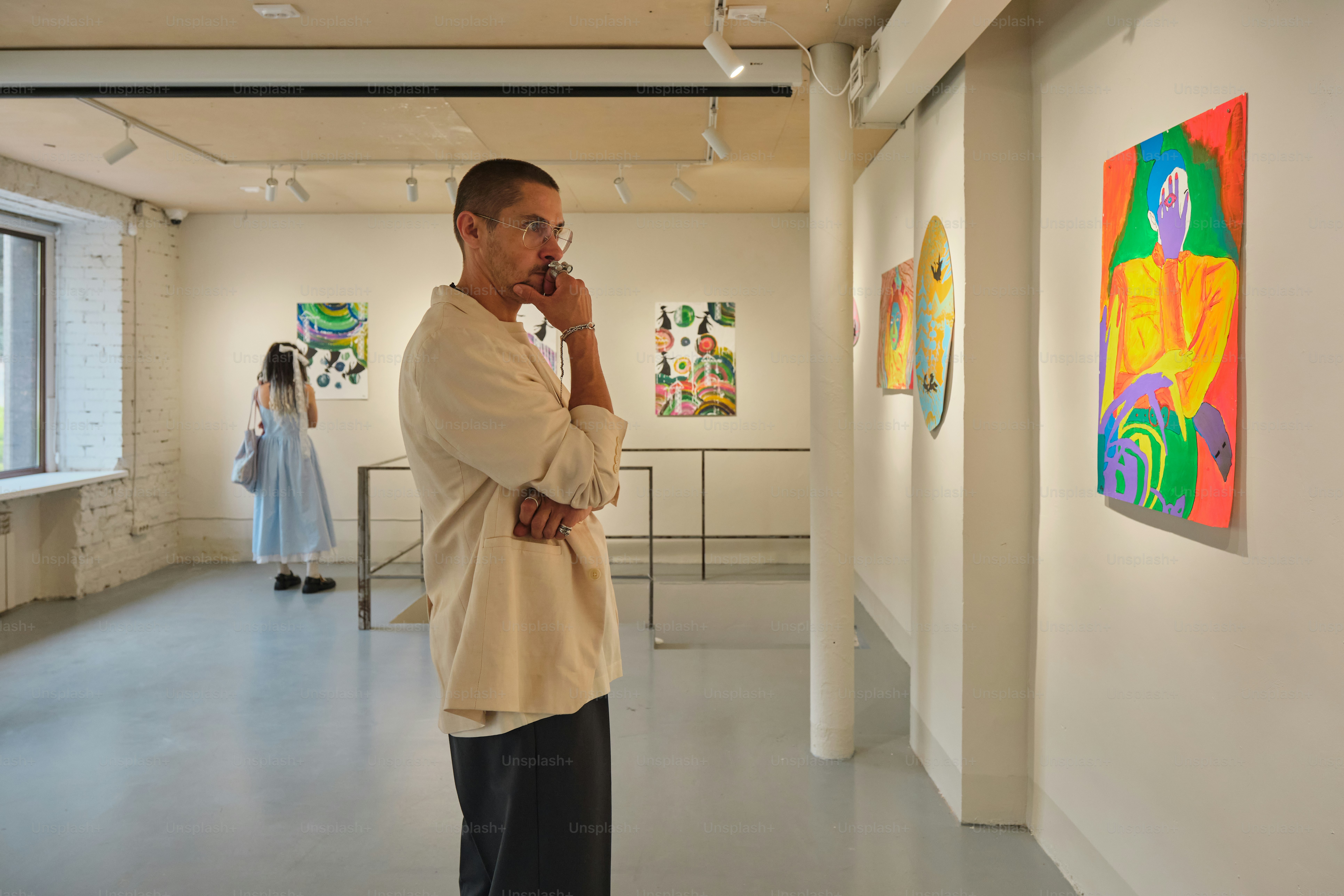 Man contemplates colorful abstract art in a gallery.