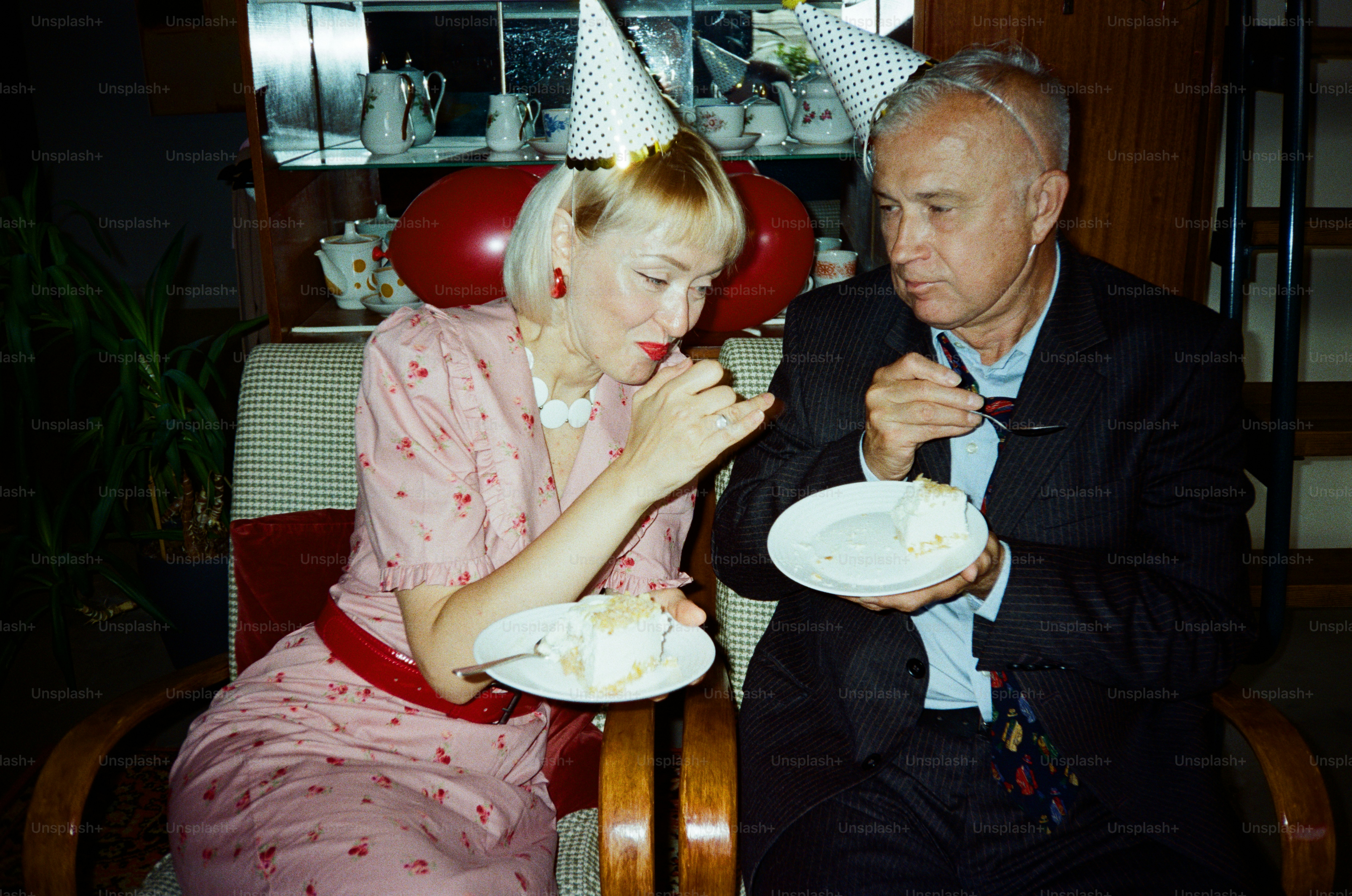 Couple eating cake at a party with party hats