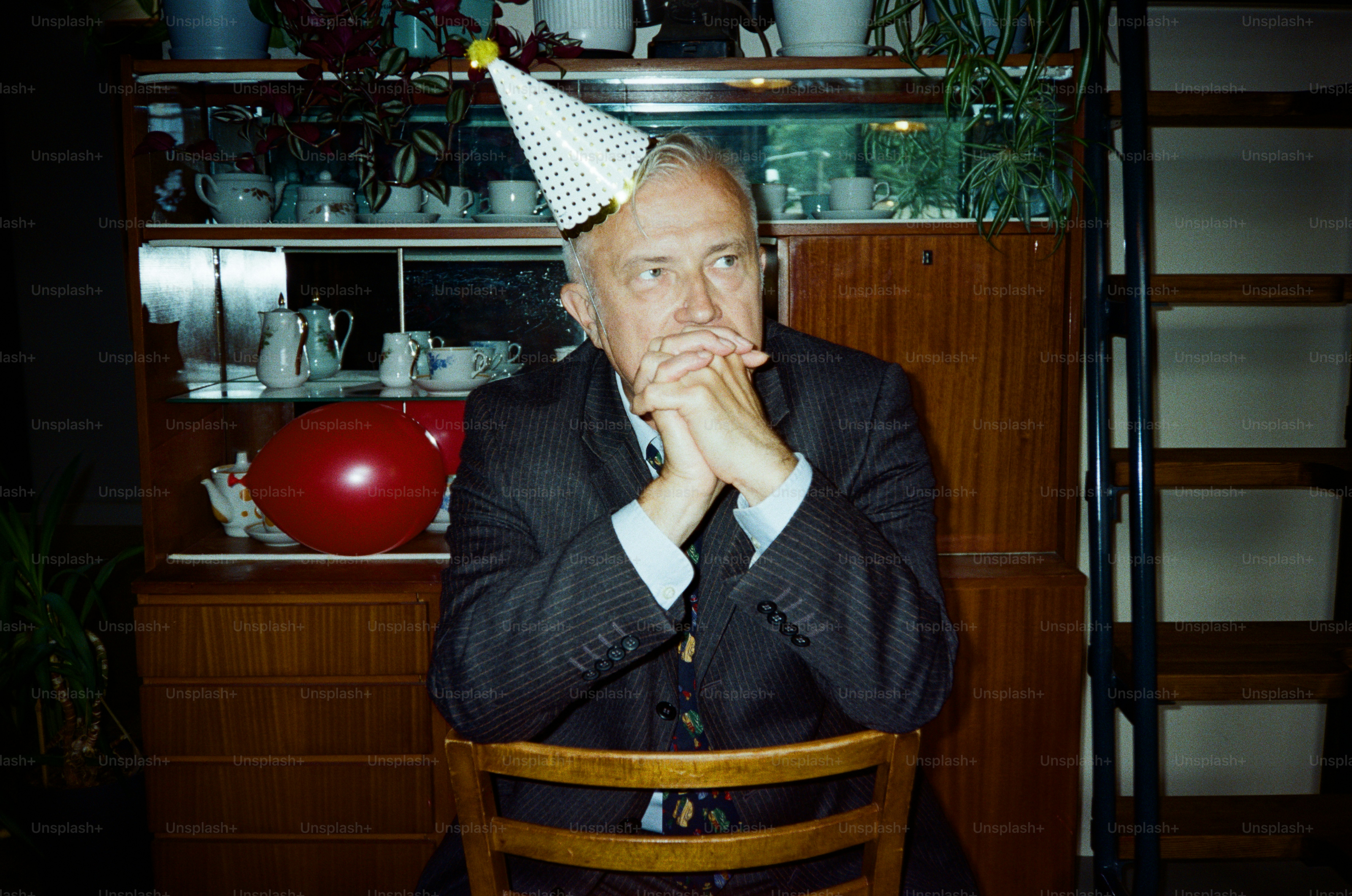 Man in party hat sits with hands clasped