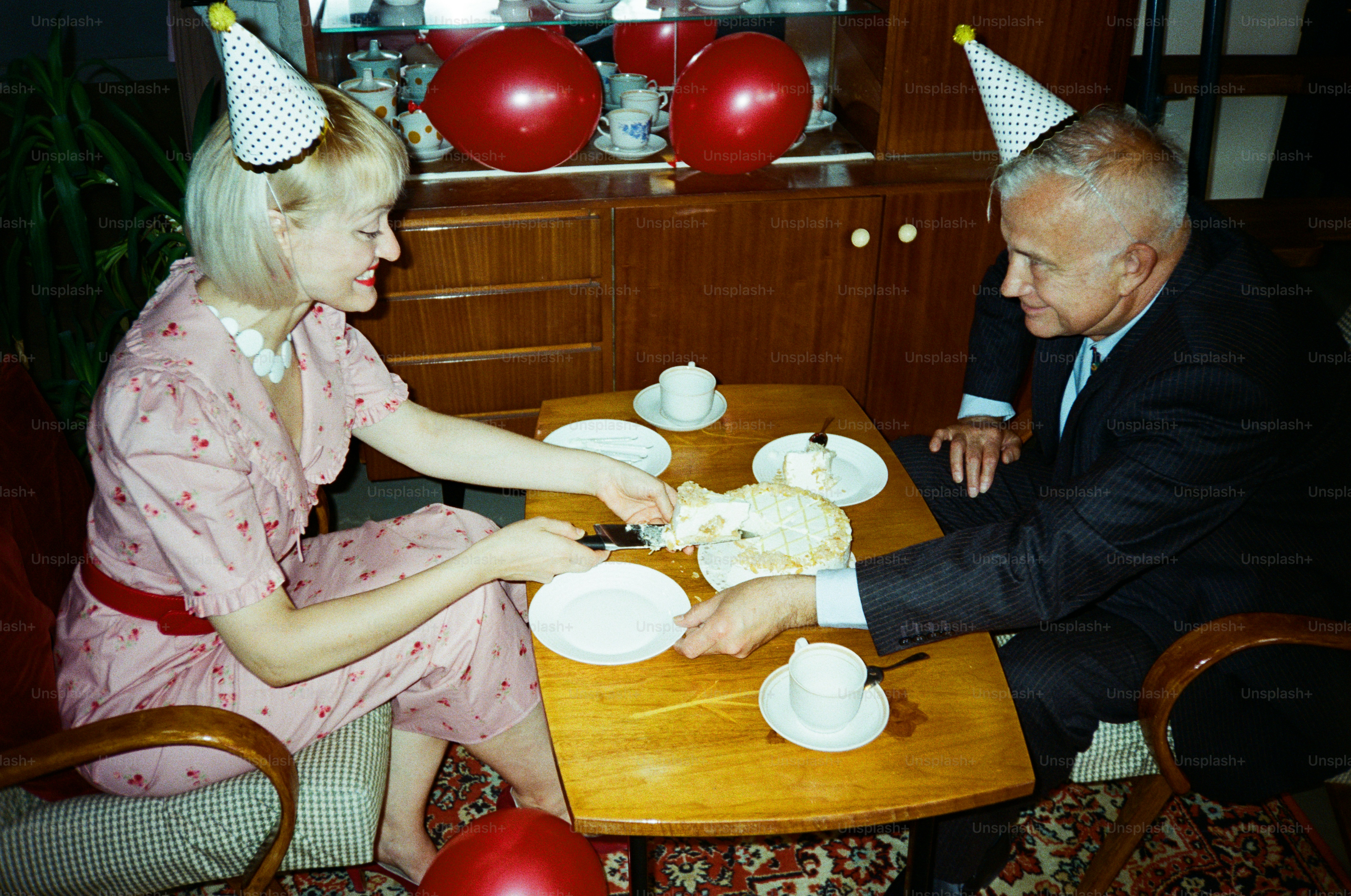 Couple wearing party hats cutting a cake