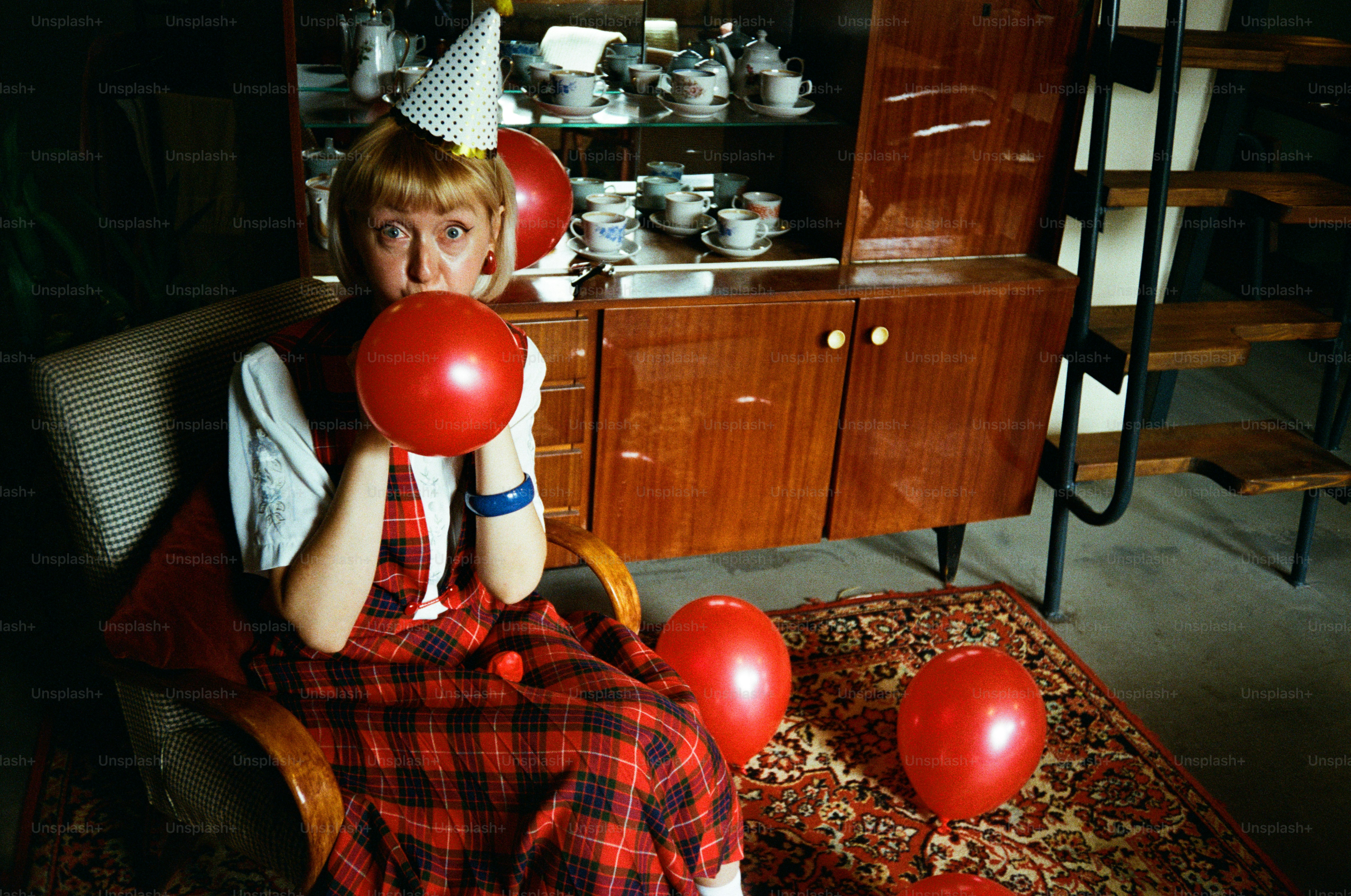 Woman in party hat blows up red balloon