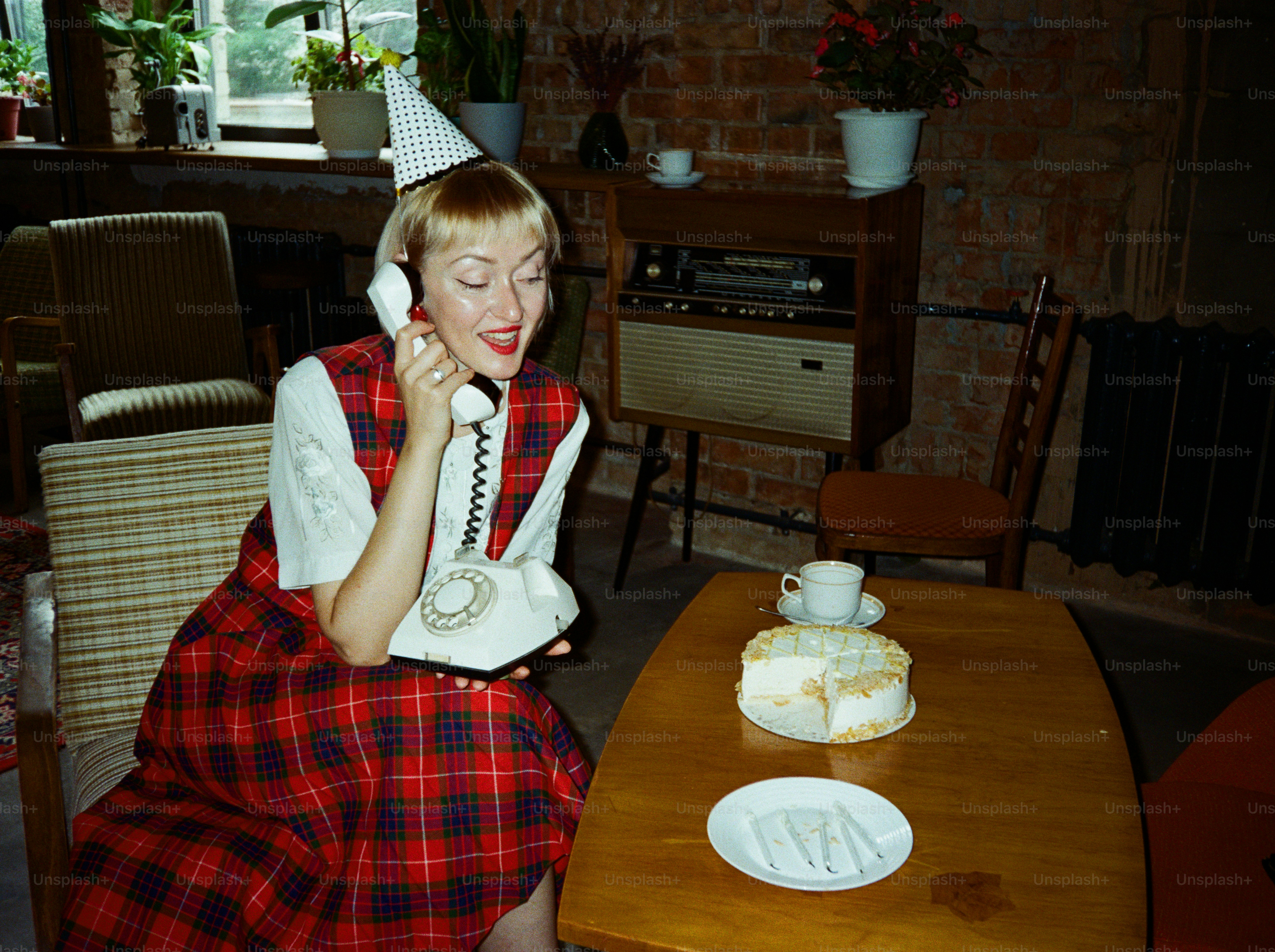 Mujer con sombrero de fiesta habla en un teléfono antiguo
