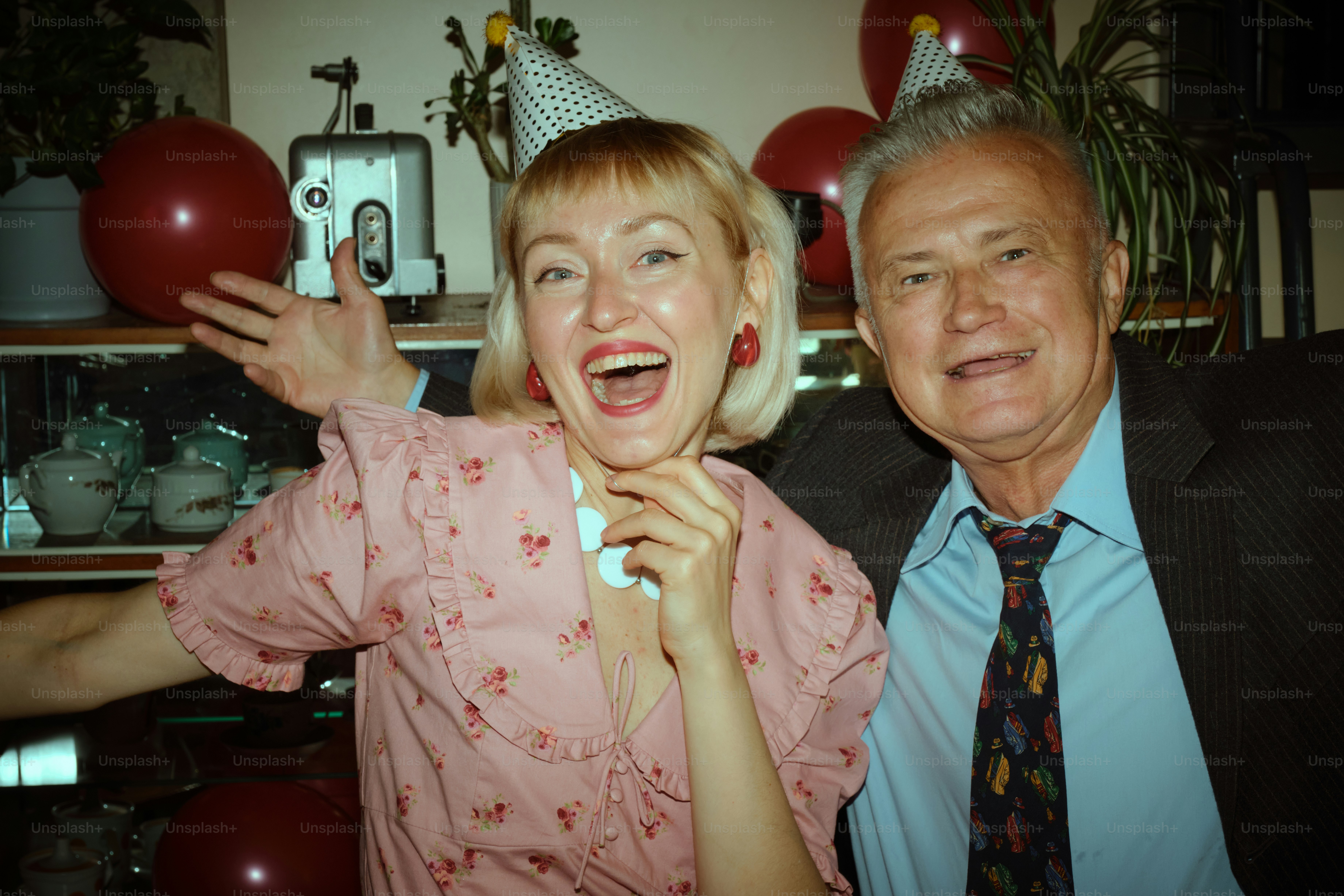 Happy couple celebrating with party hats and balloons