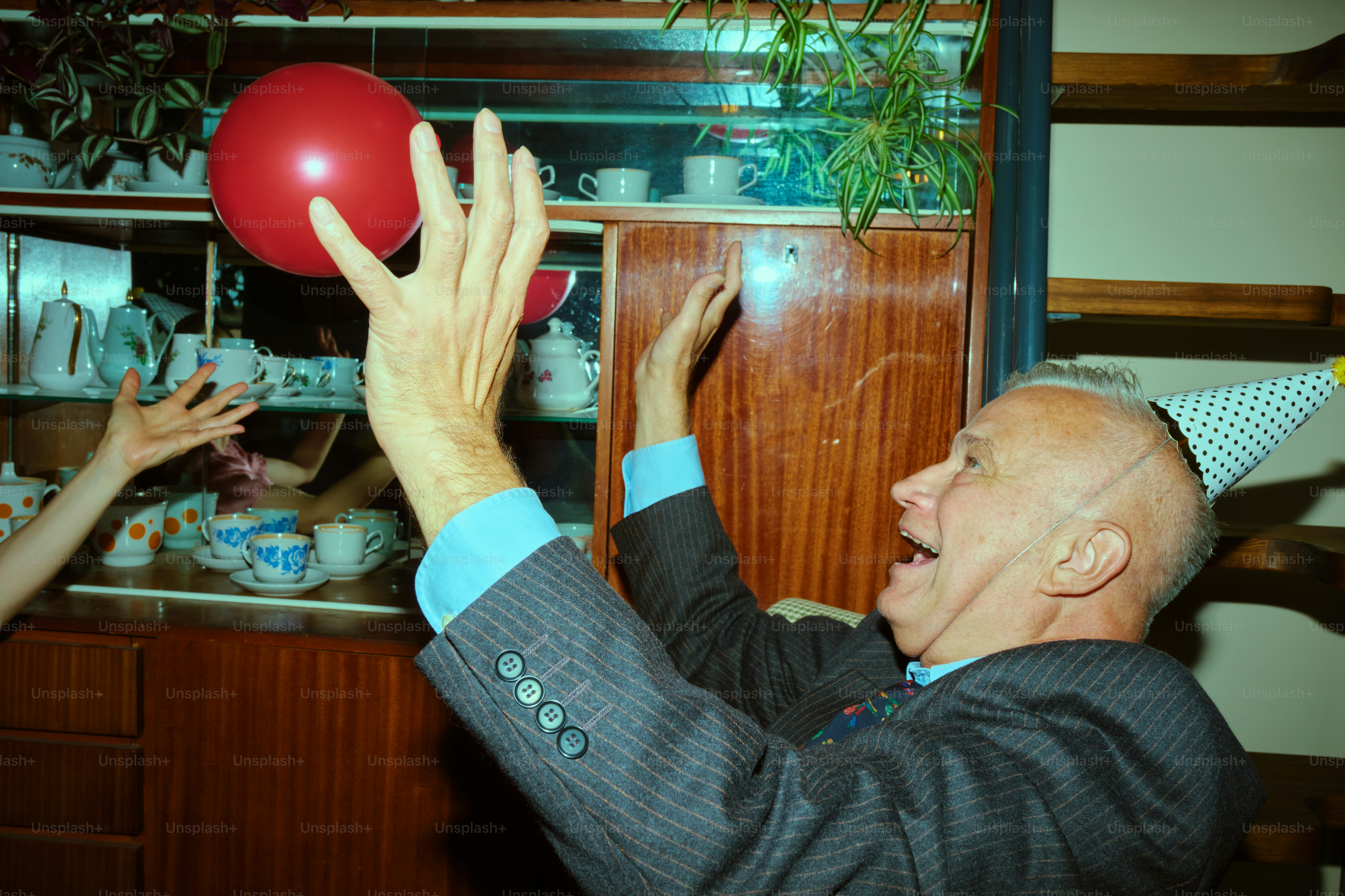 Man in party hat throws red balloon at celebration
