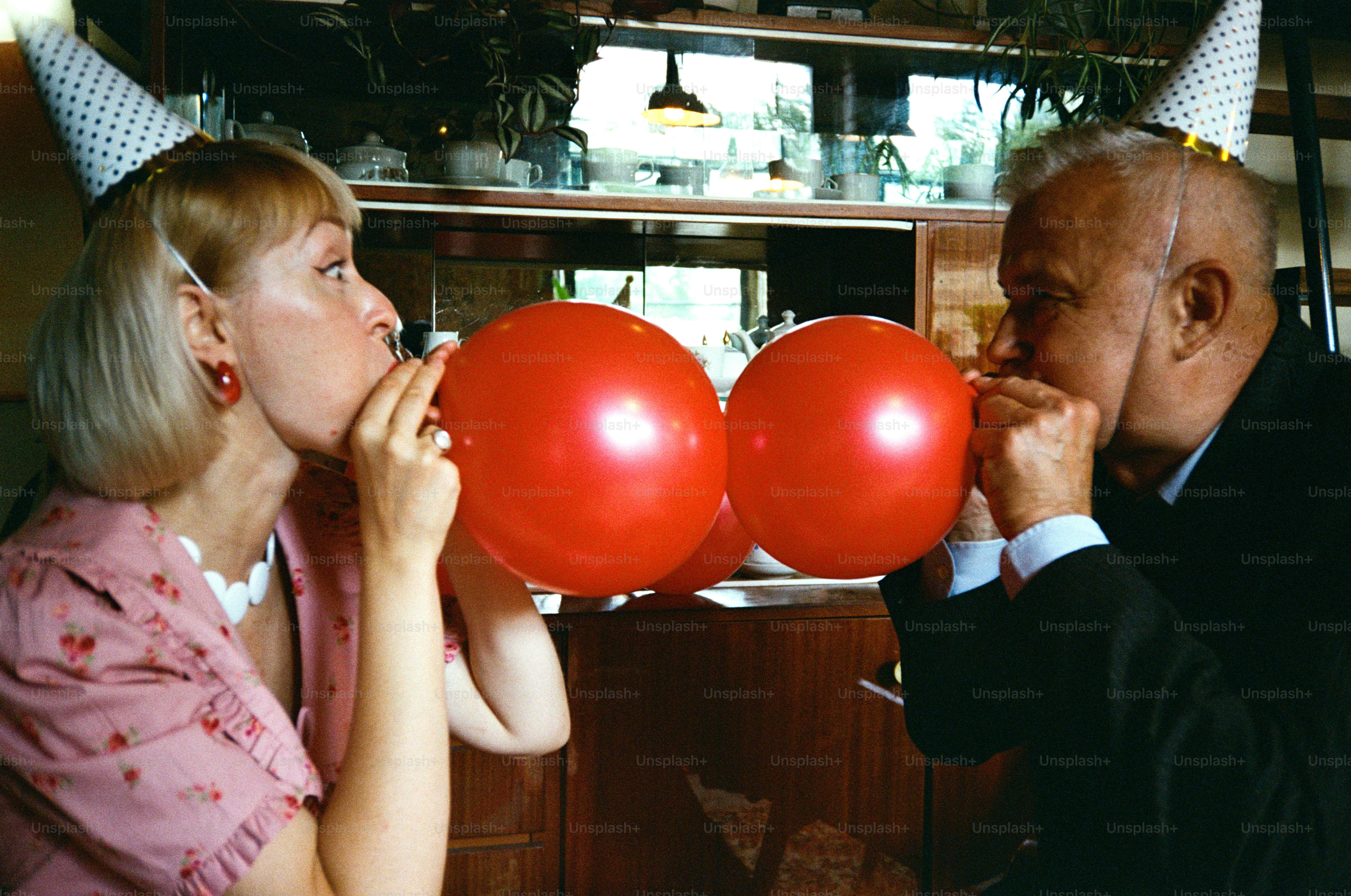 Couple blowing up red balloons at a party