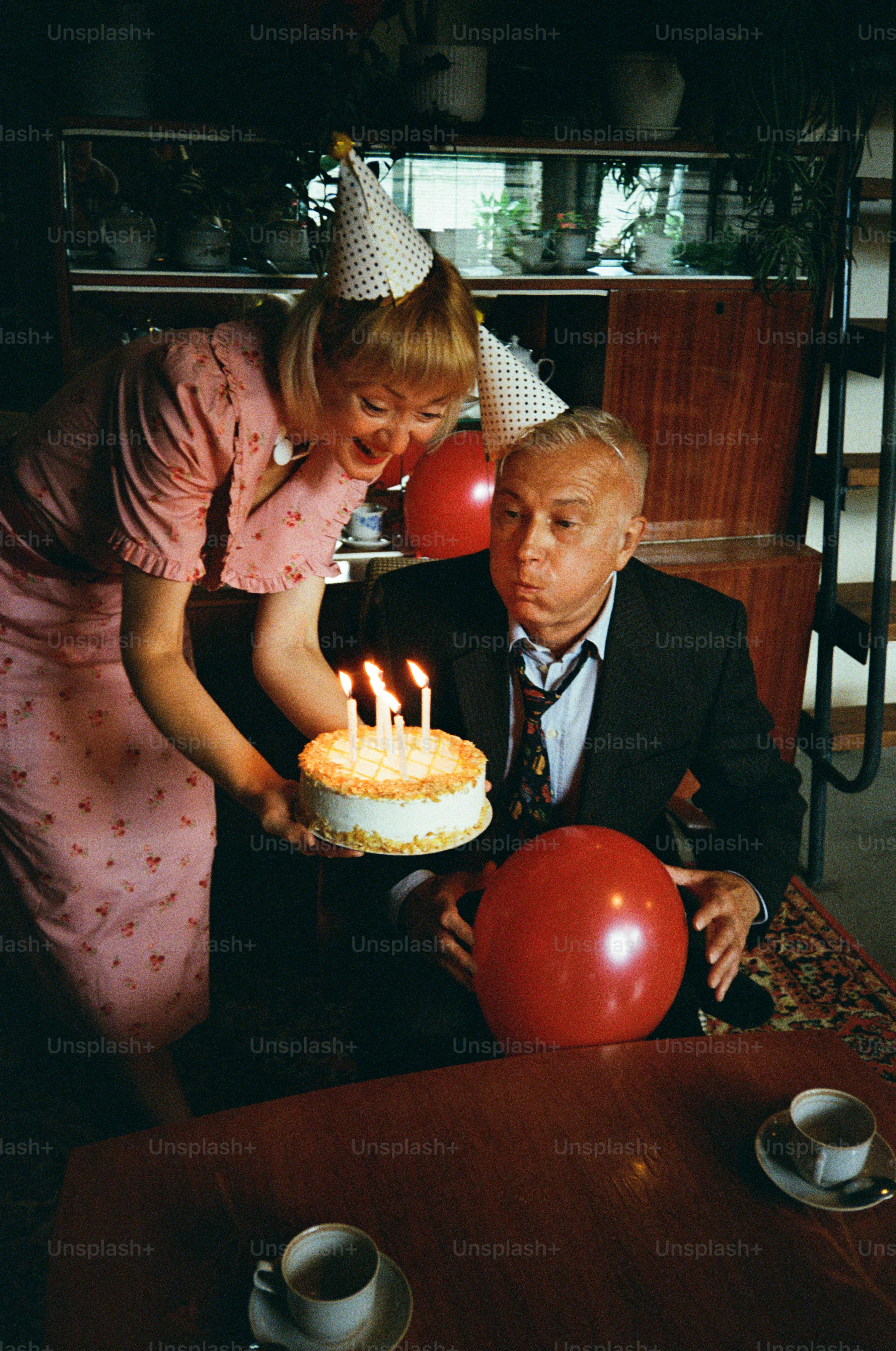 Man blows out candles on birthday cake with woman