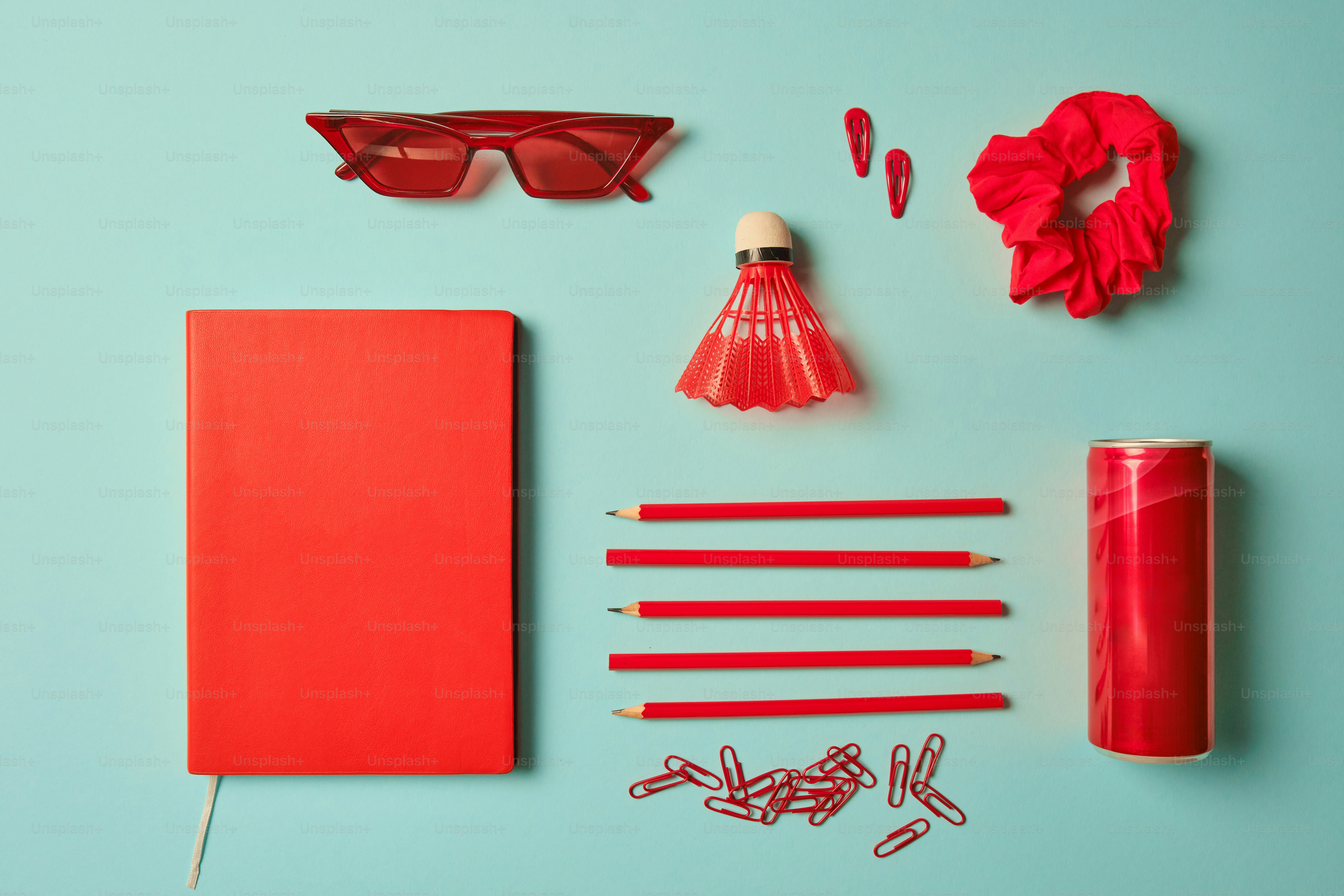 Red stationery and accessories arranged on a blue background.