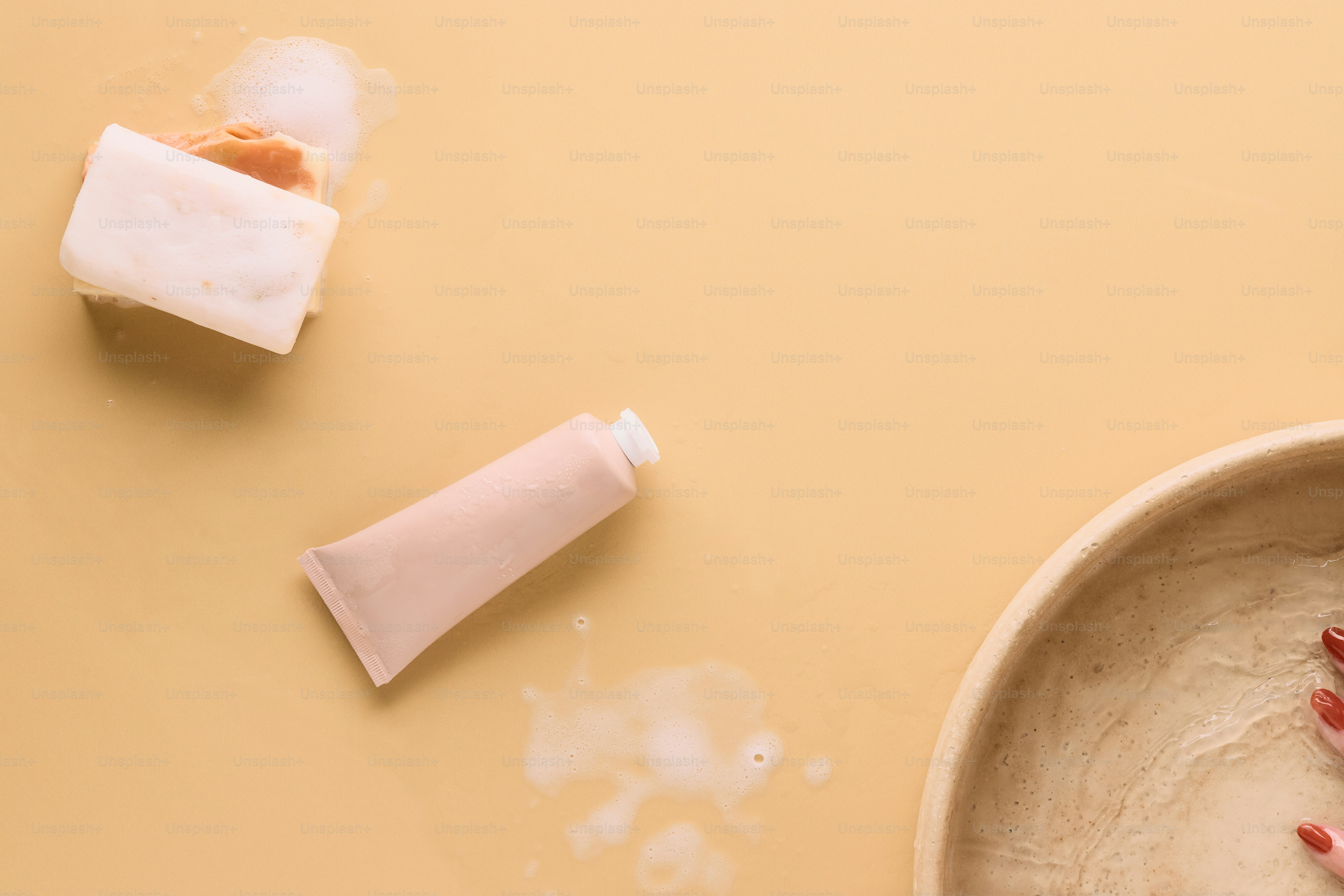Seife, Lotion und Schüssel auf pfirsichfarbenem Hintergrund