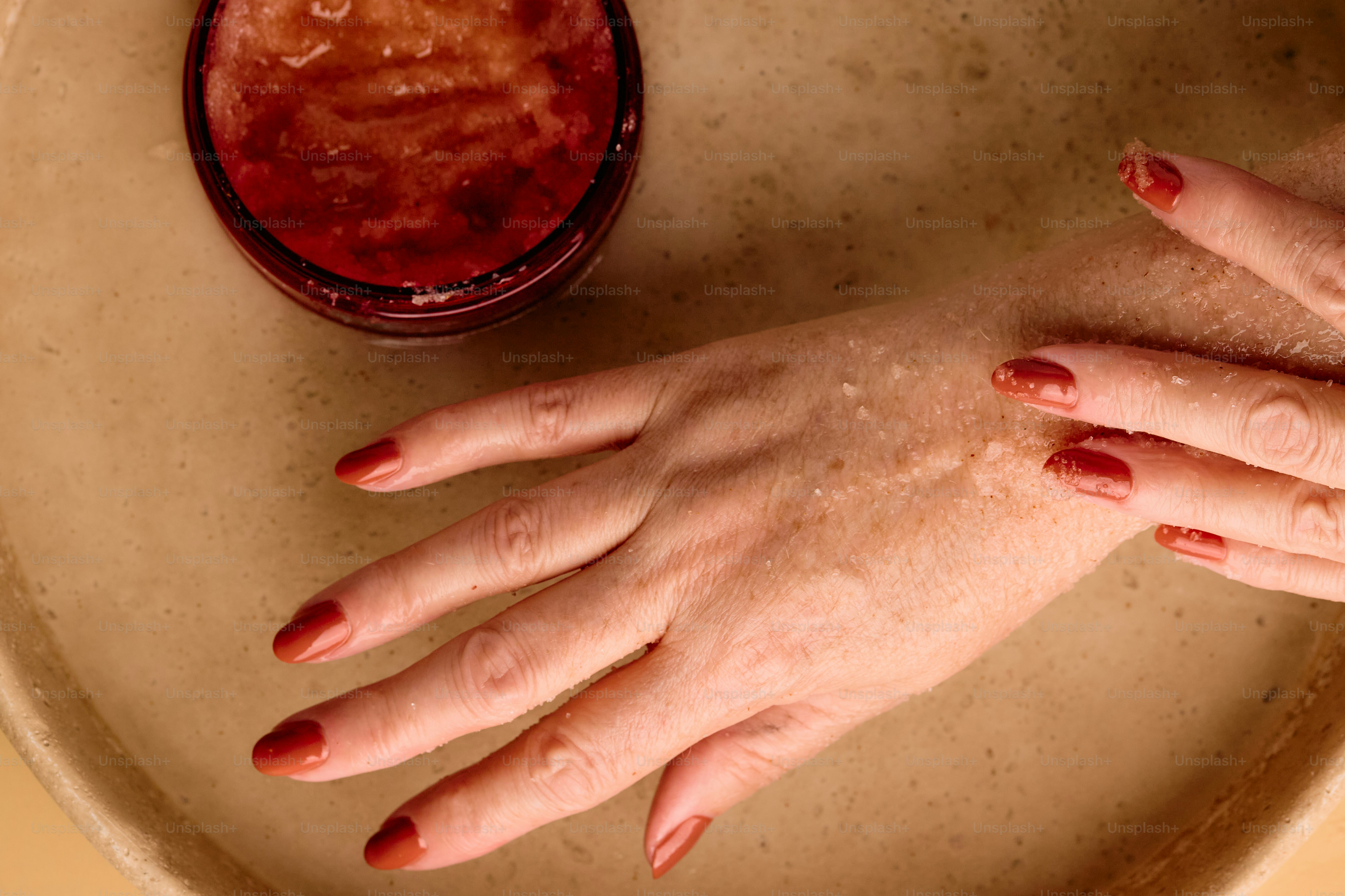 Hände mit rotem Nagellack in Seifenwasser