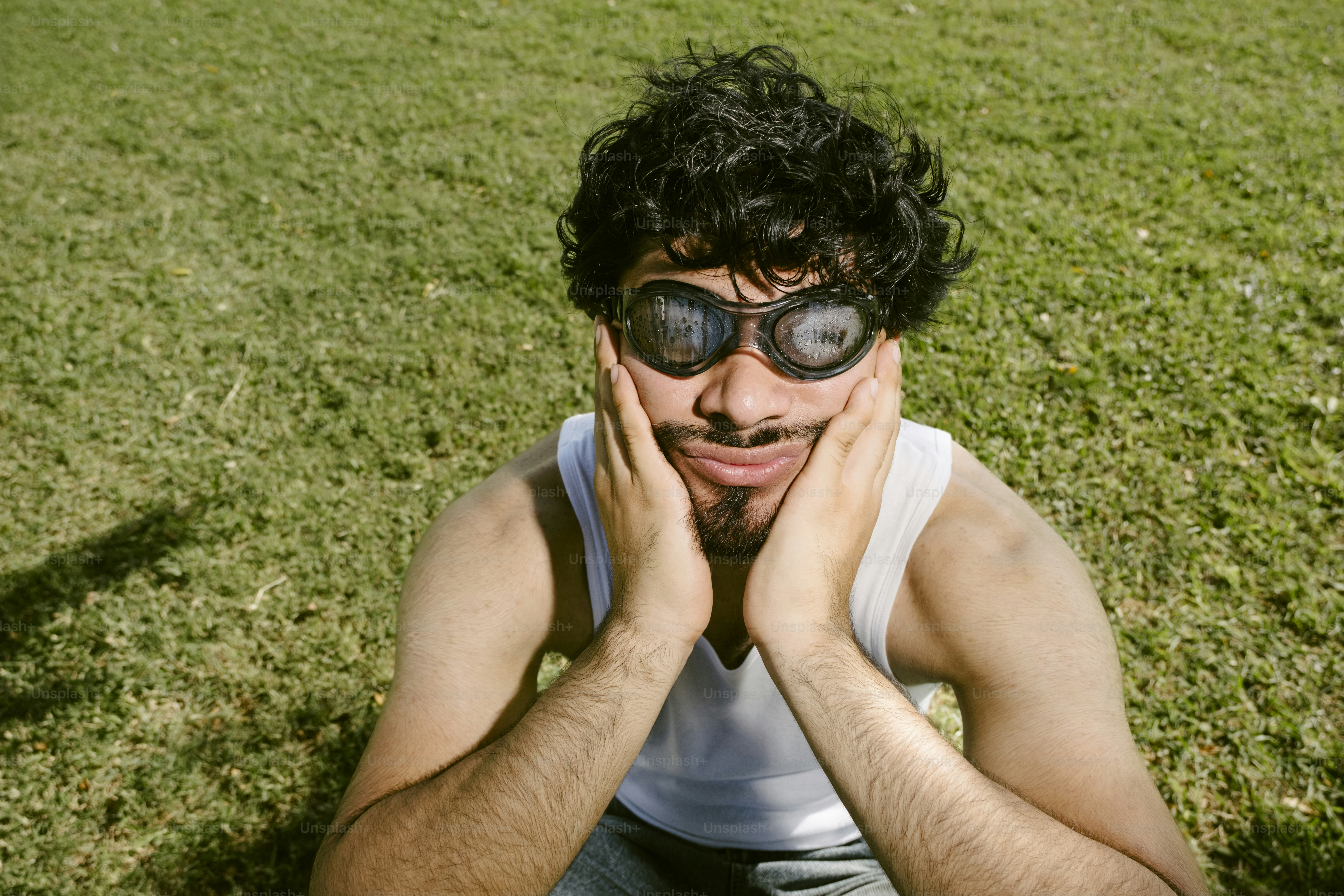 Homem com óculos escuros segura rosto em campo gramado