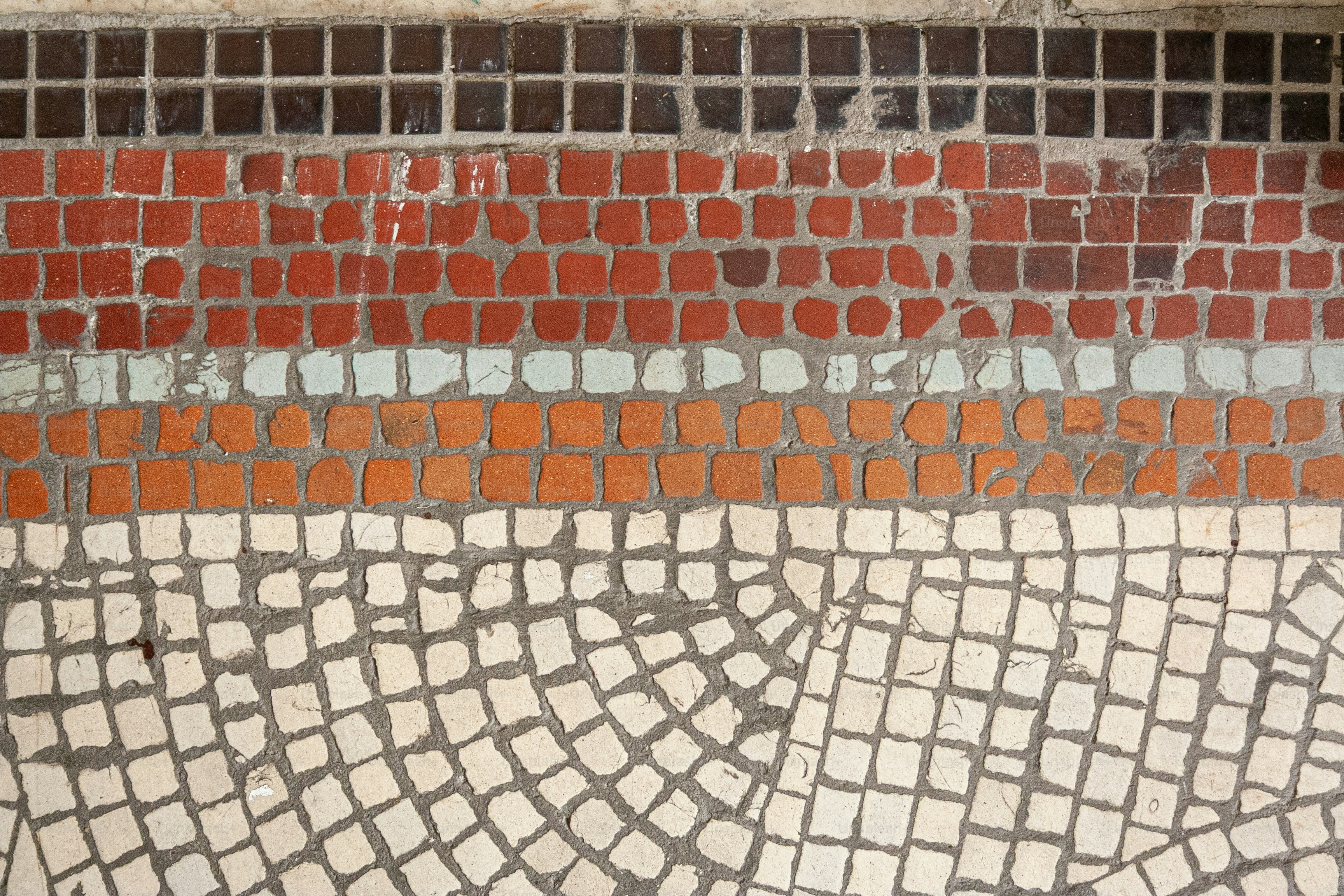 Patrón de mosaico con rayas de azulejos rojos, naranjas y blancos.