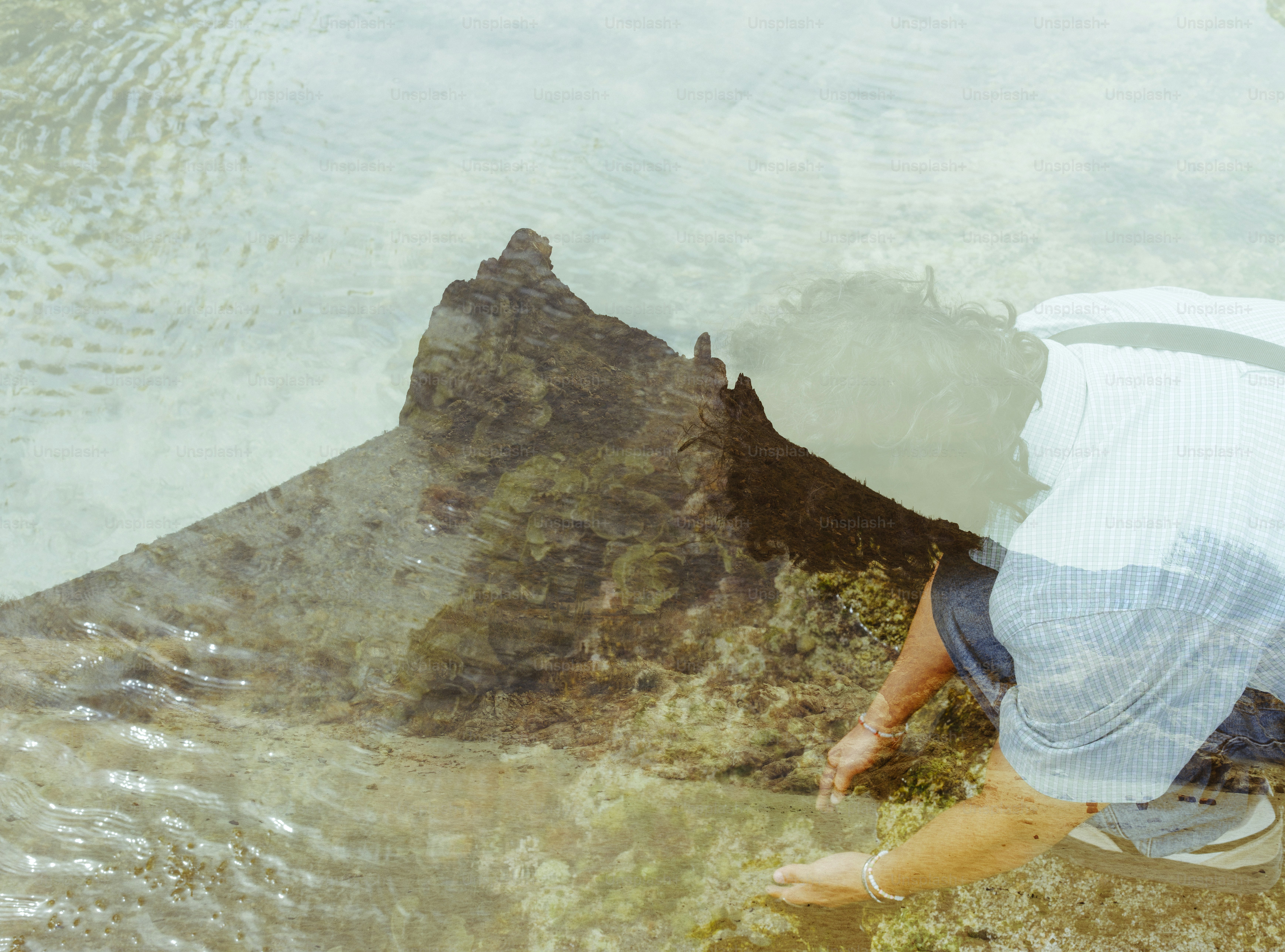 Person reaching towards a submerged rock formation