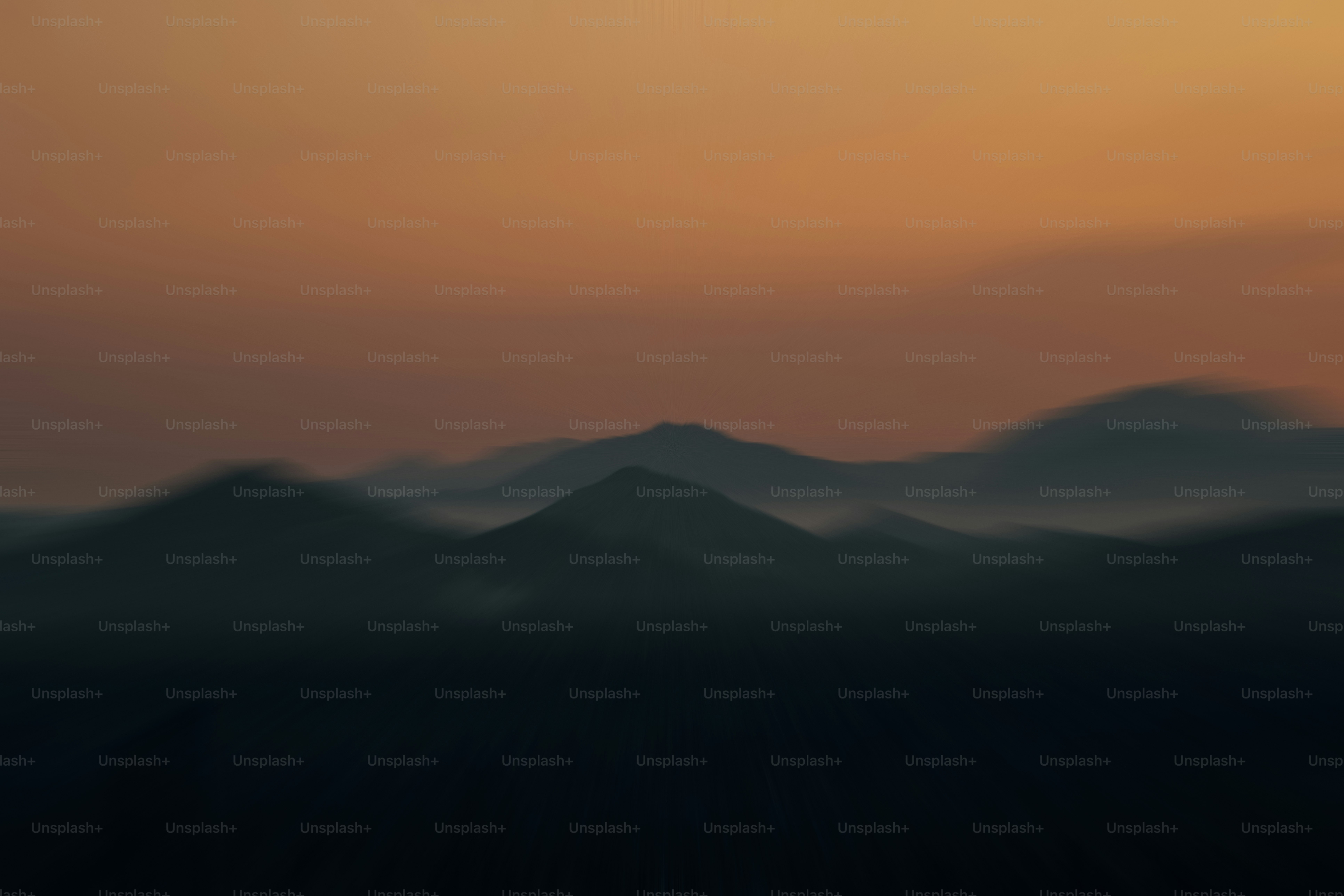 Misty mountains silhouetted against an orange sky