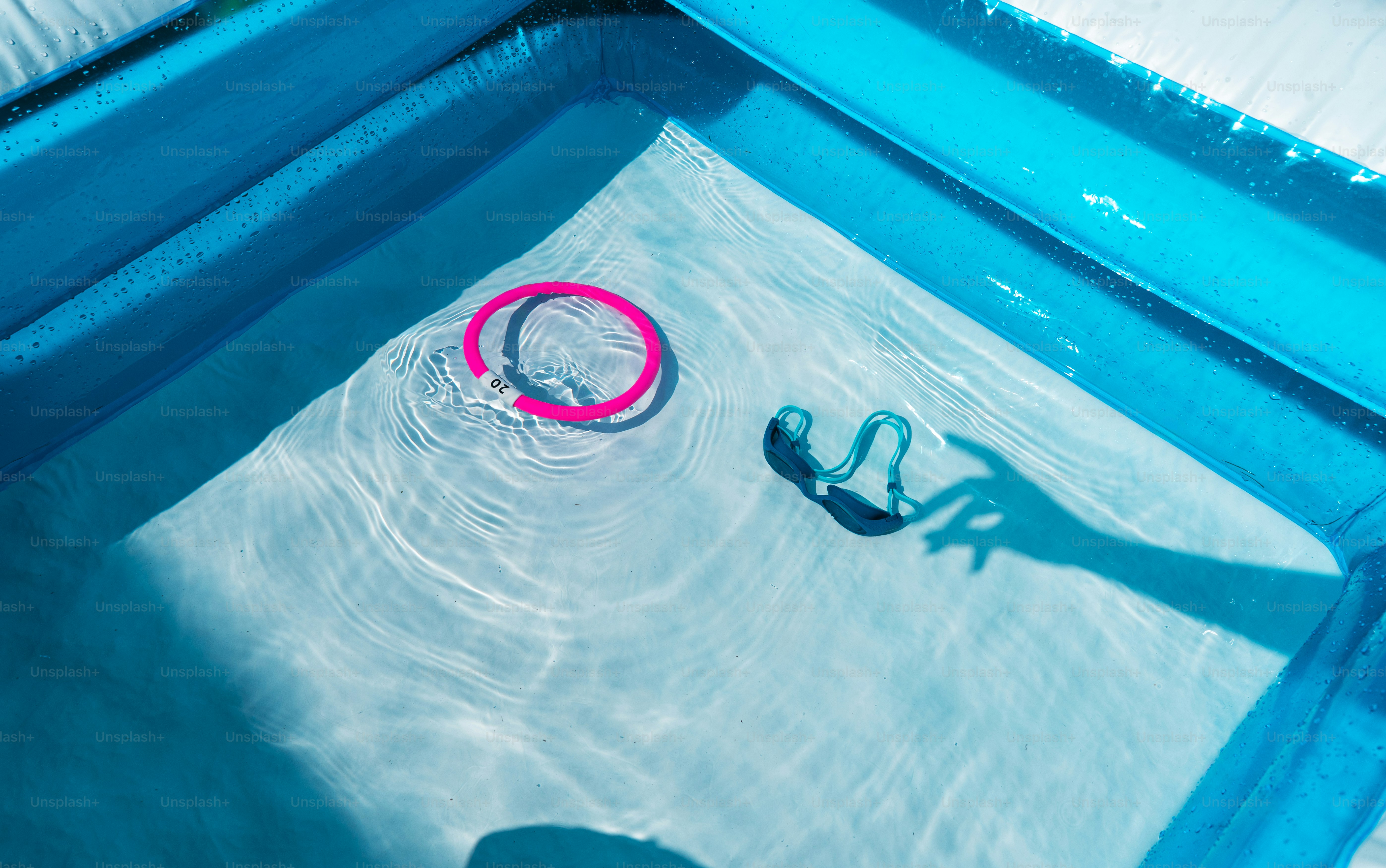 El anillo rosa y las gafas flotan en aguas poco profundas de la piscina