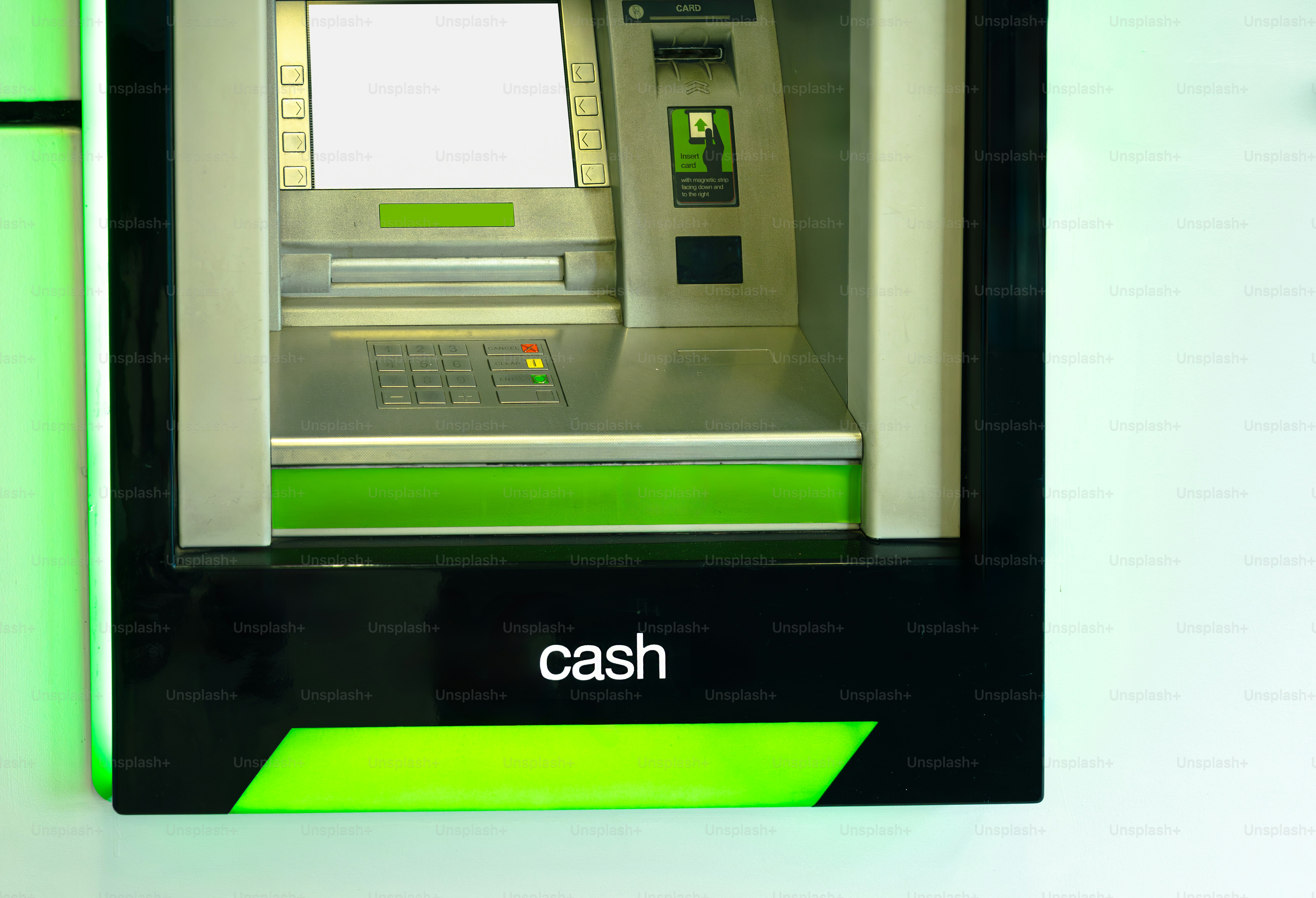 An atm machine dispenses cash with green accents.