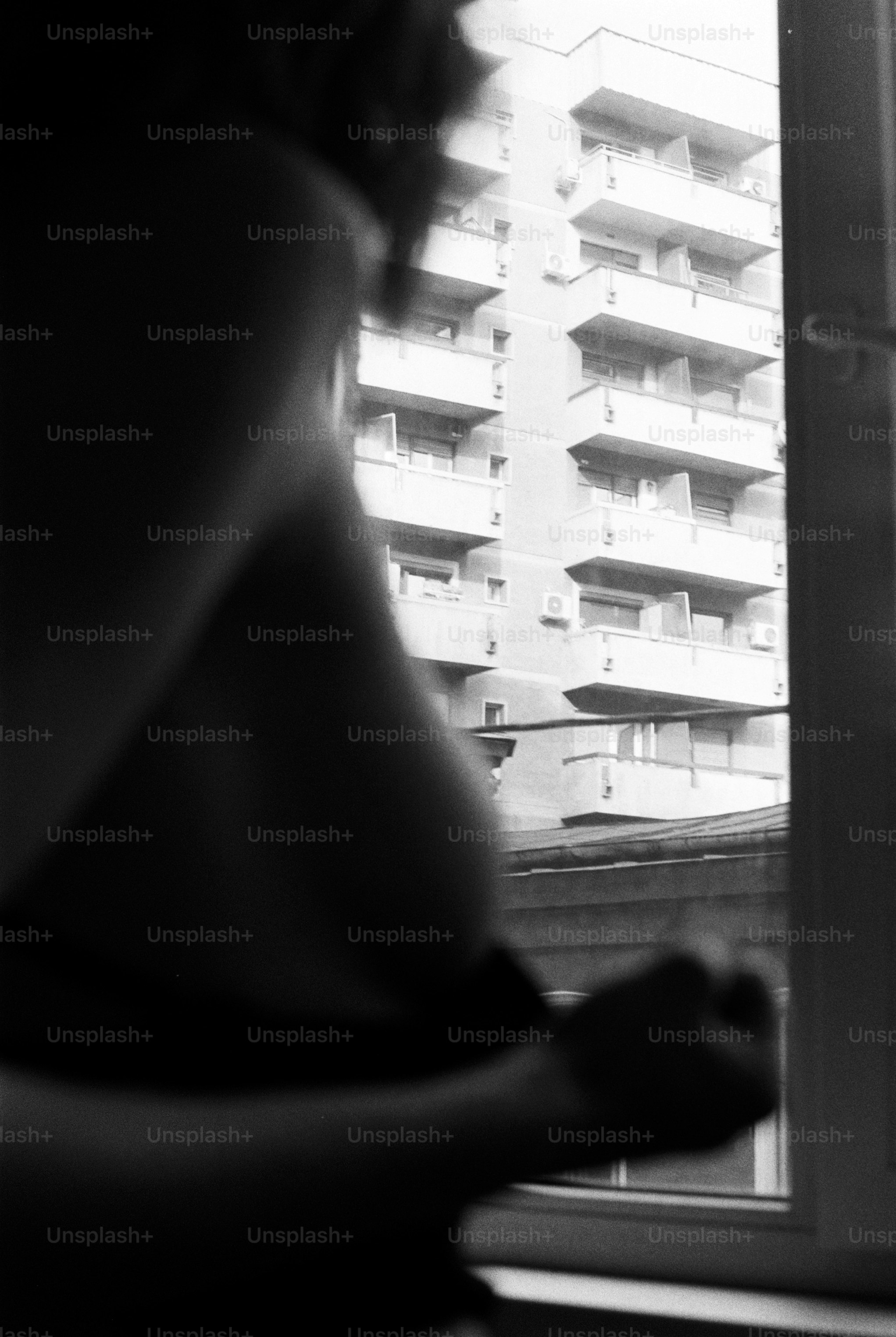 Woman looking out window at apartment building