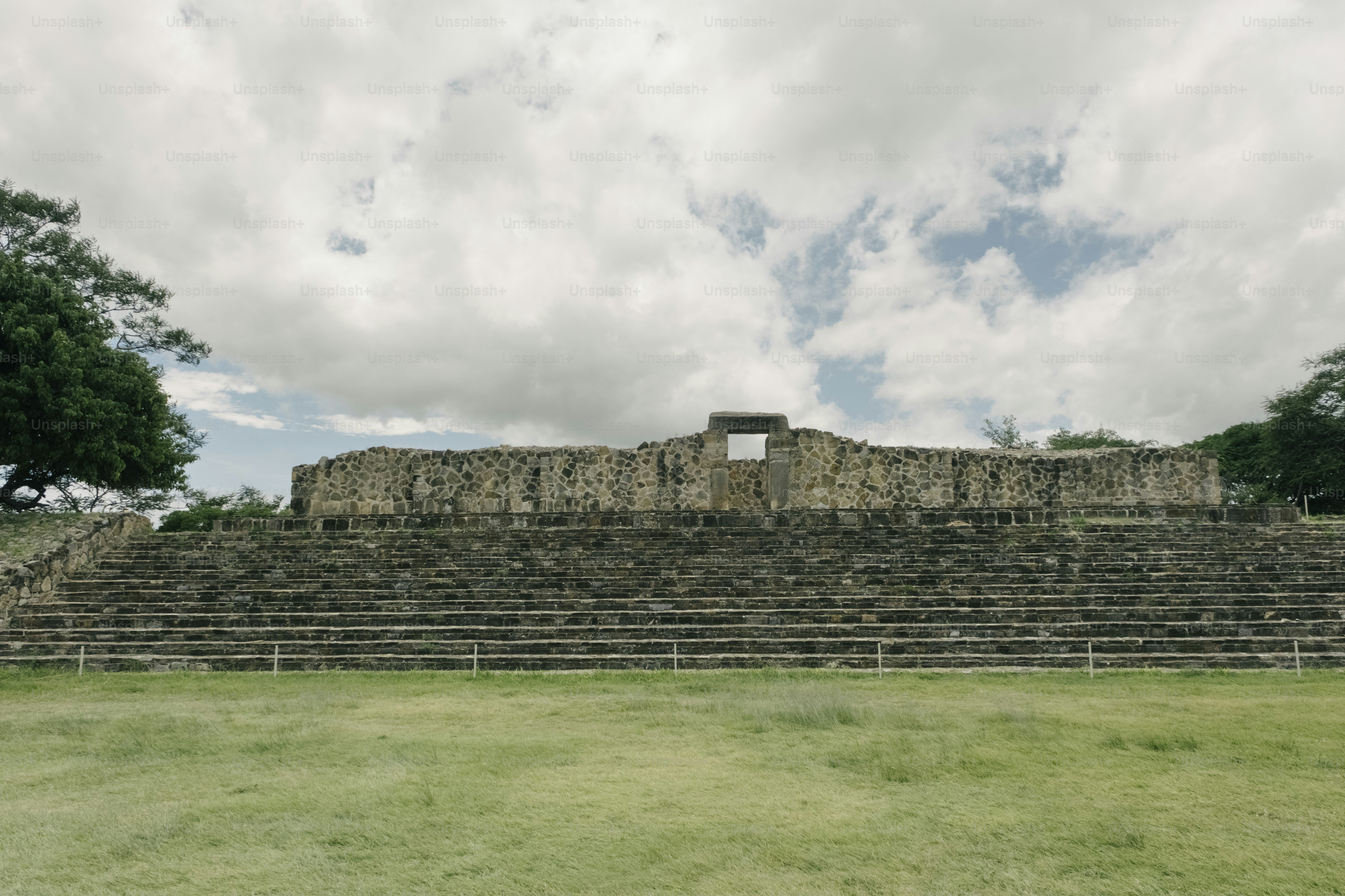 Ancient stone stadium with grassy field and cloudy sky