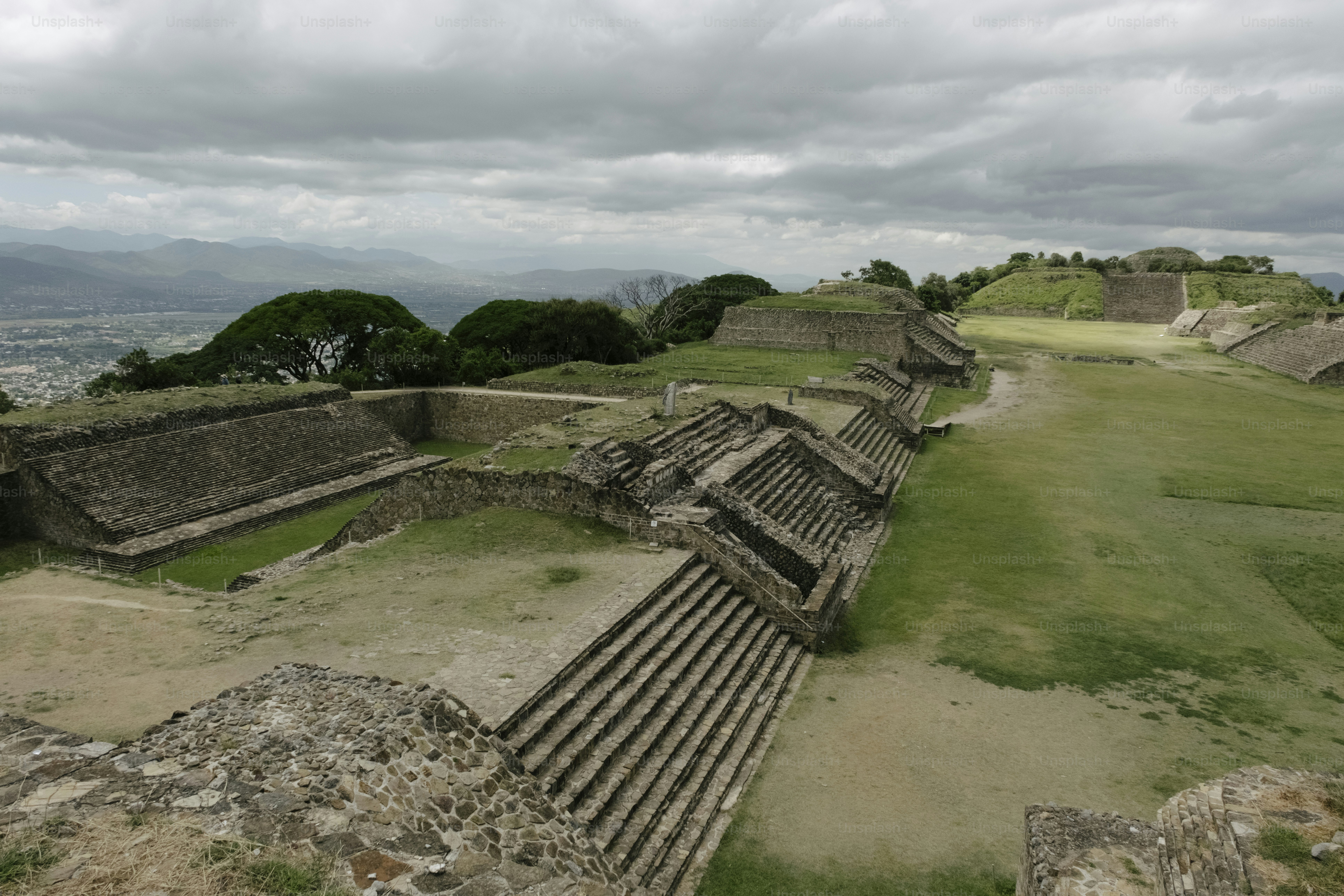 Ancient stone ruins on a grassy hillside under cloudy sky