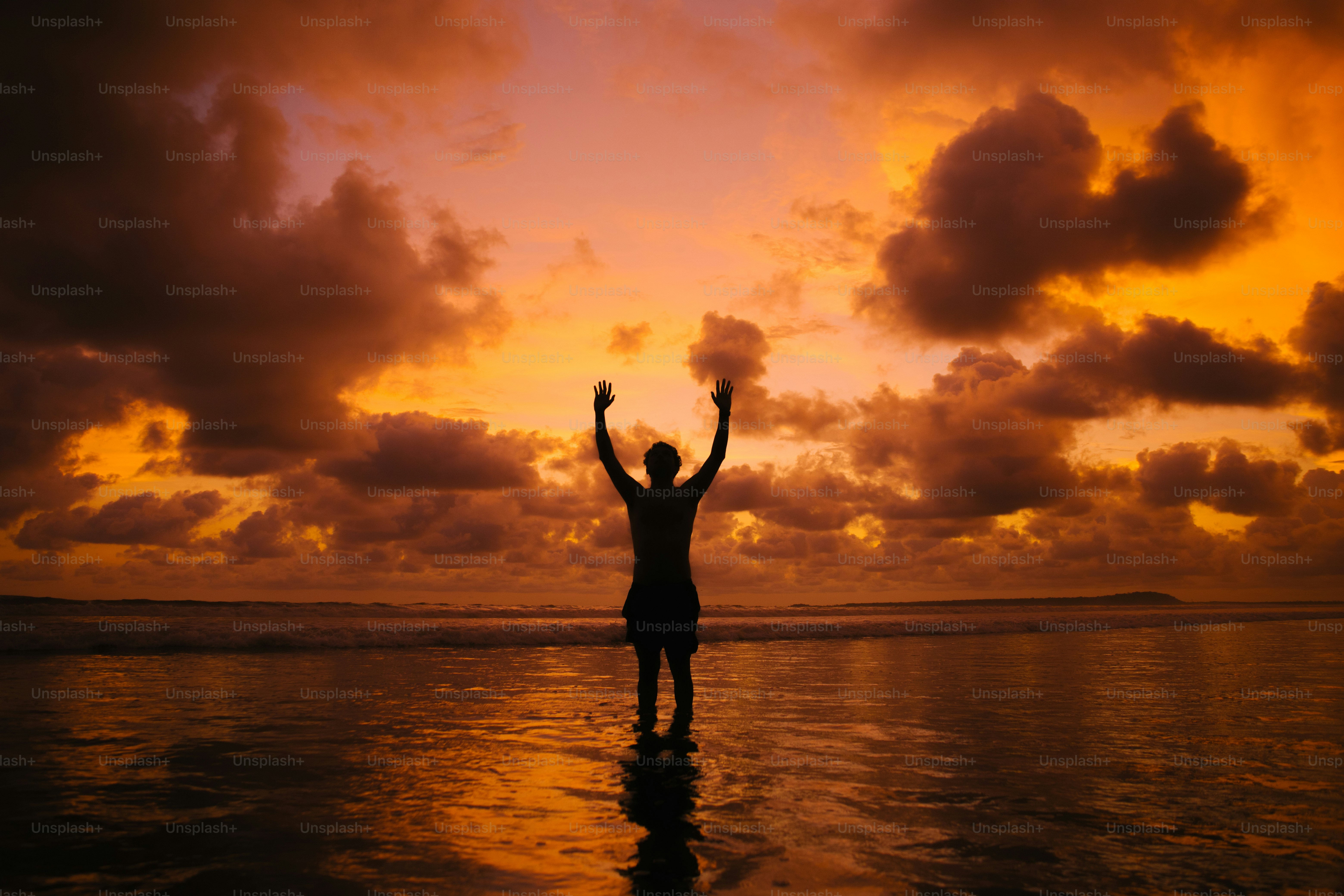 Silhouette of person with arms raised at sunset