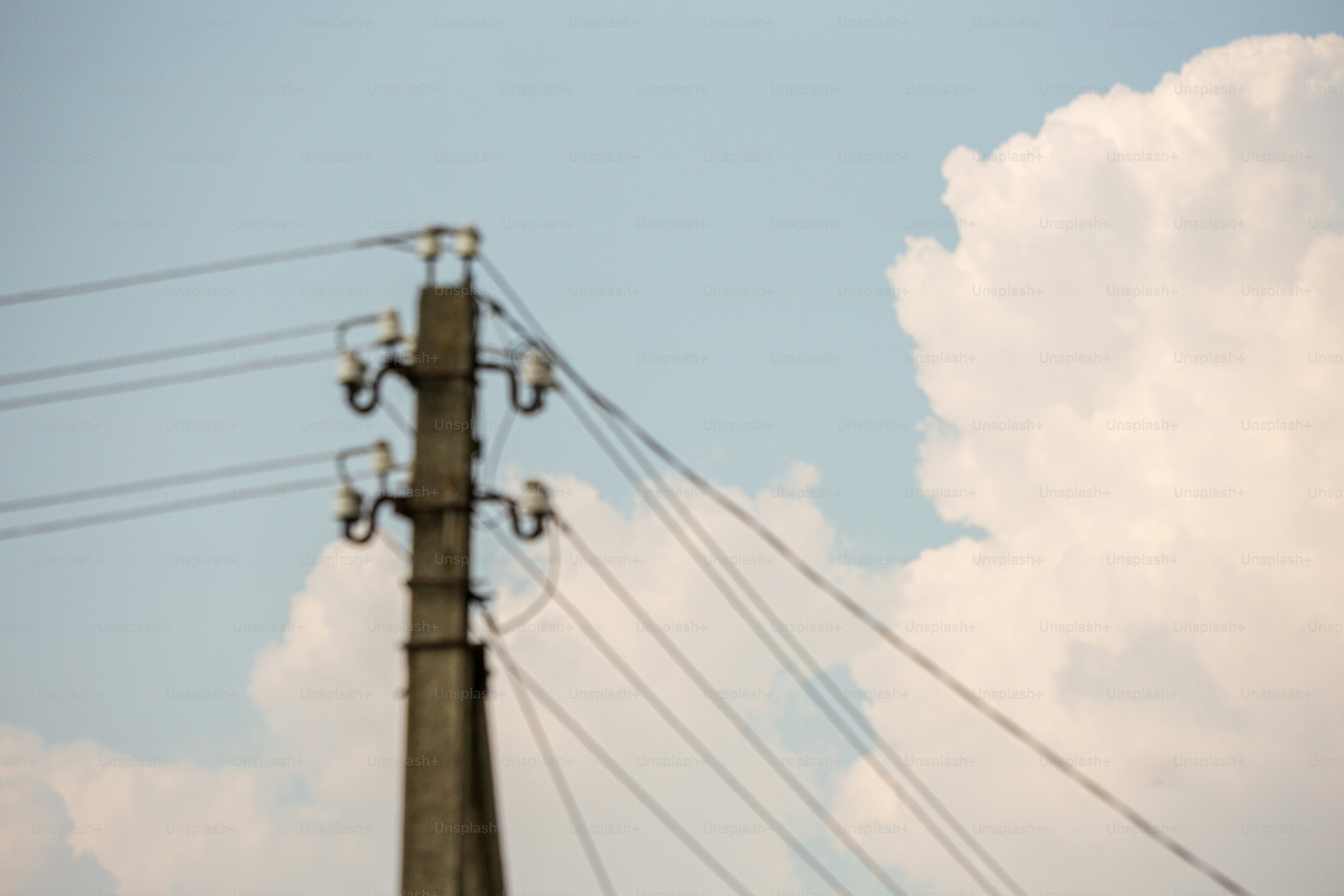 Concrete power pole with wires against cloudy sky