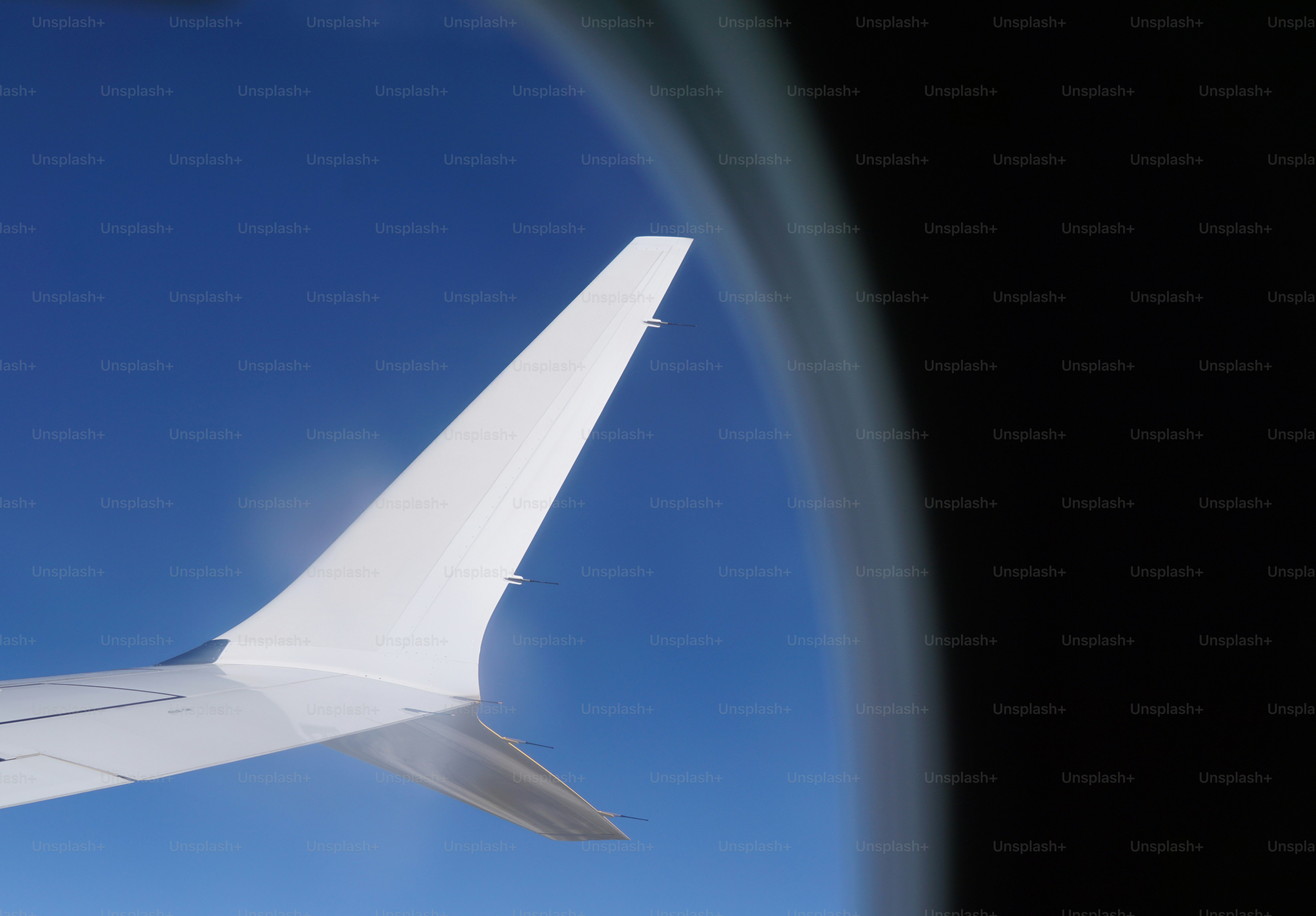 Airplane wing against a clear blue sky