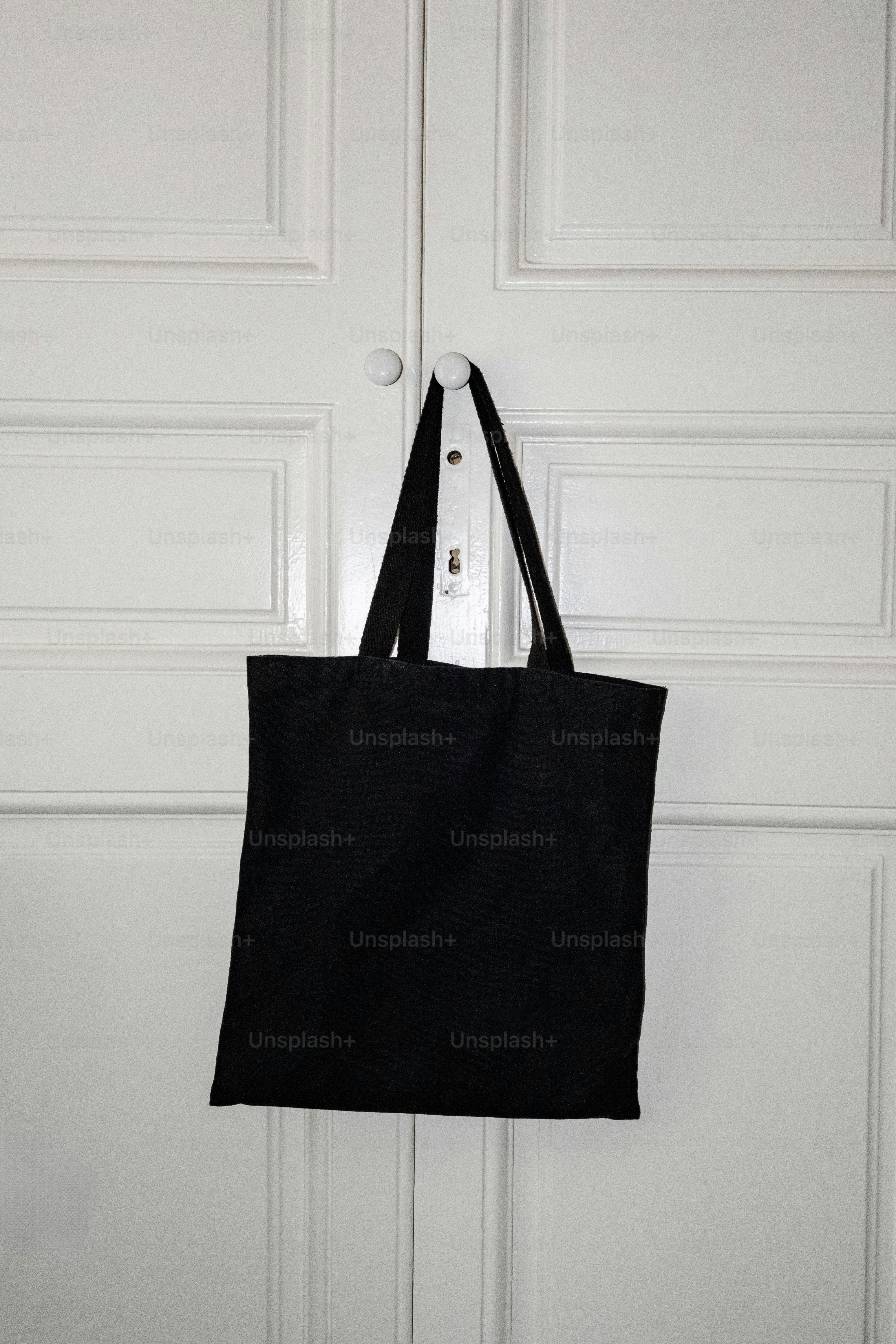 Tas jinjing hitam tergantung di pintu putih