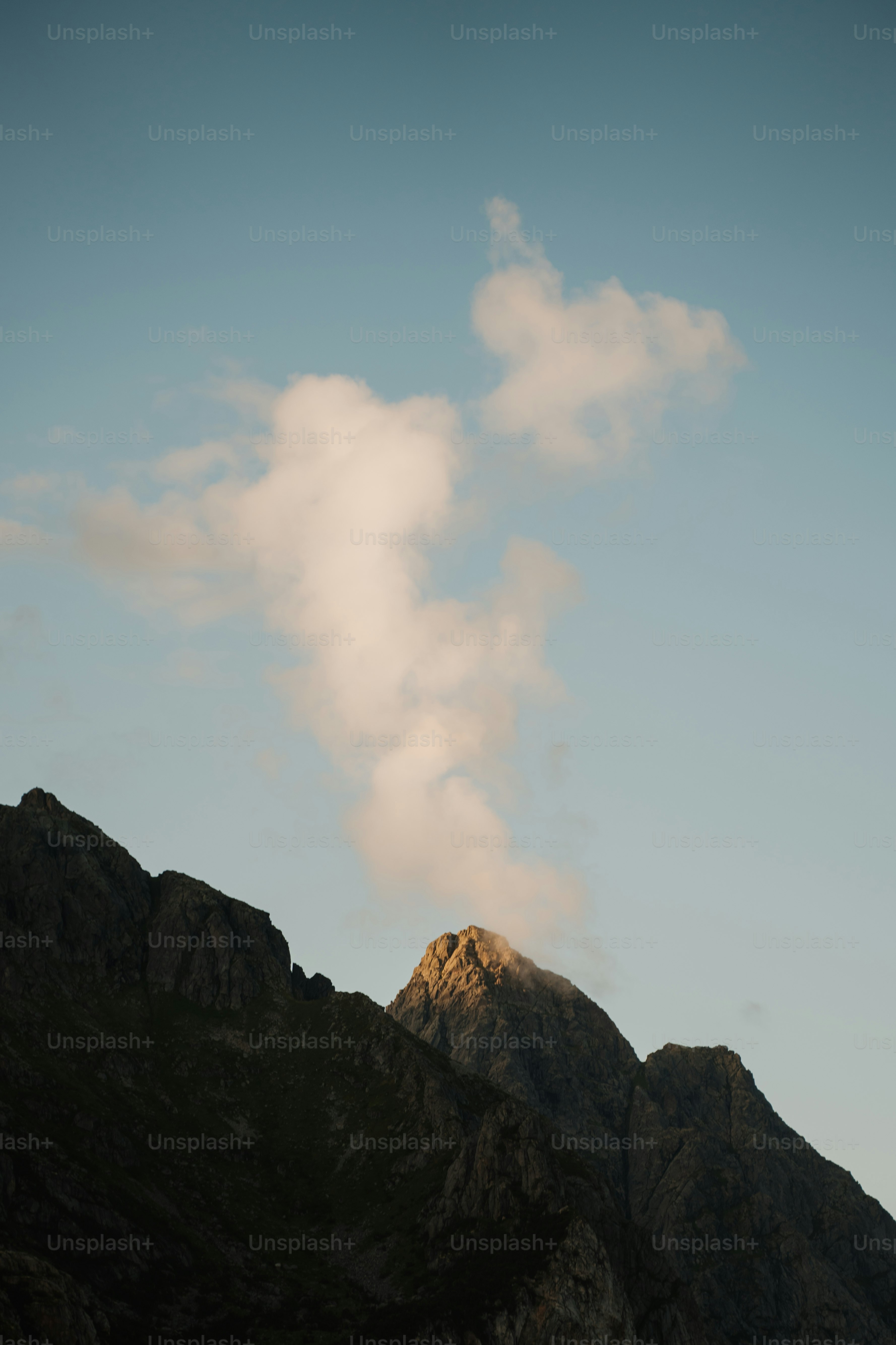 Mountain peak with smoke against a clear blue sky