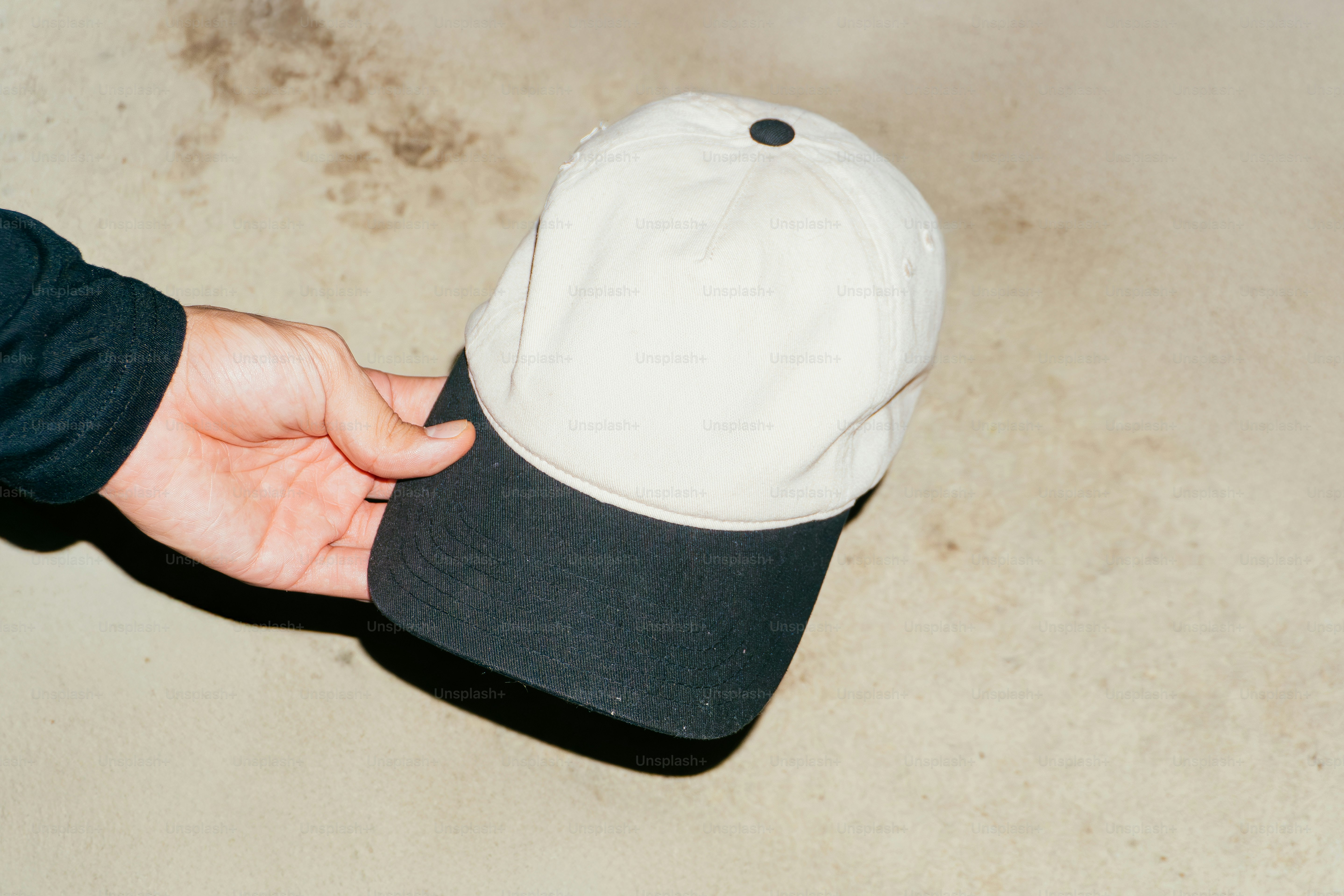 Hand holding a two-tone baseball cap