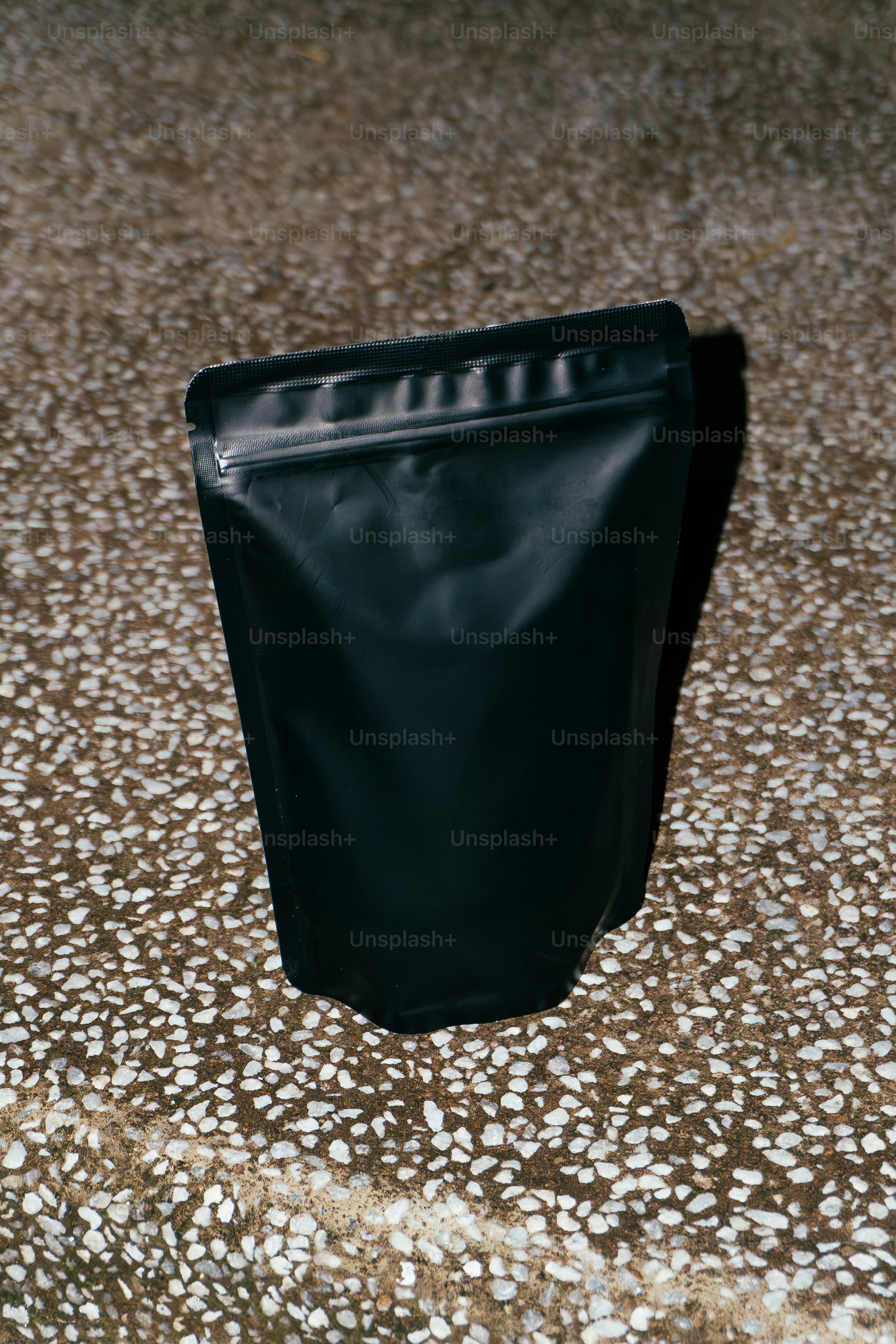 A black pouch stands on a speckled surface.