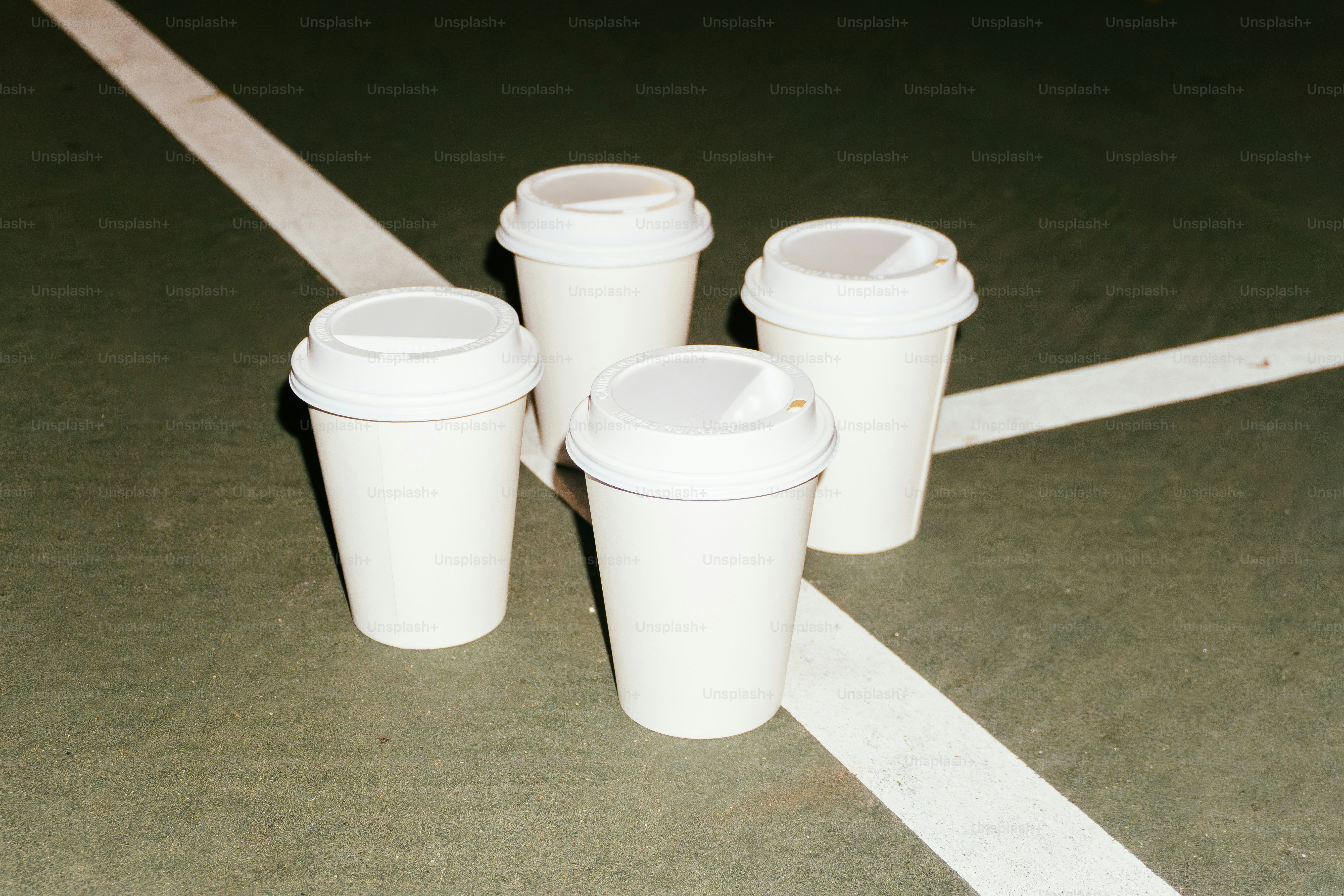 Four white coffee cups on a court.