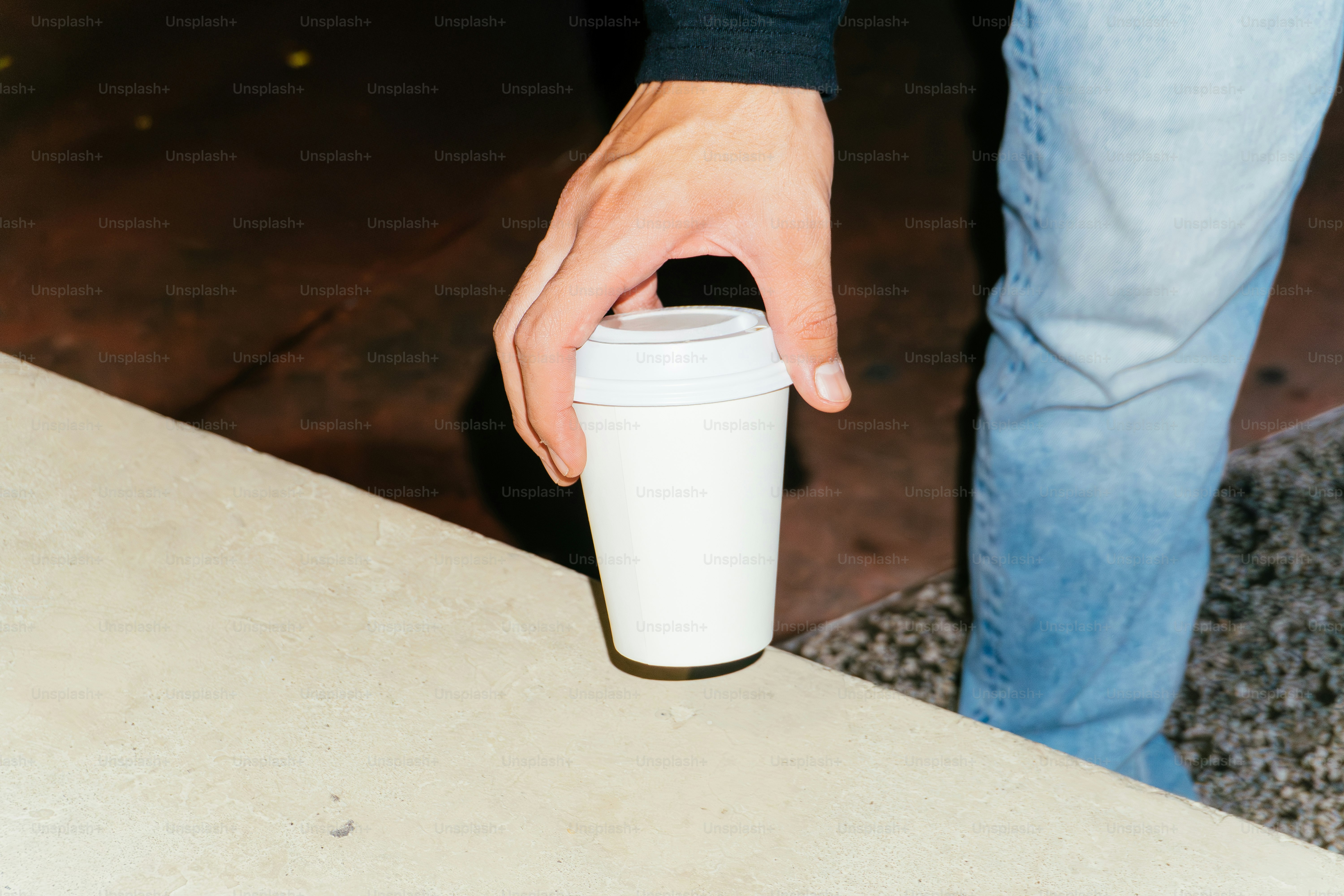 Mano che tiene una tazza di caffè usa e getta bianca