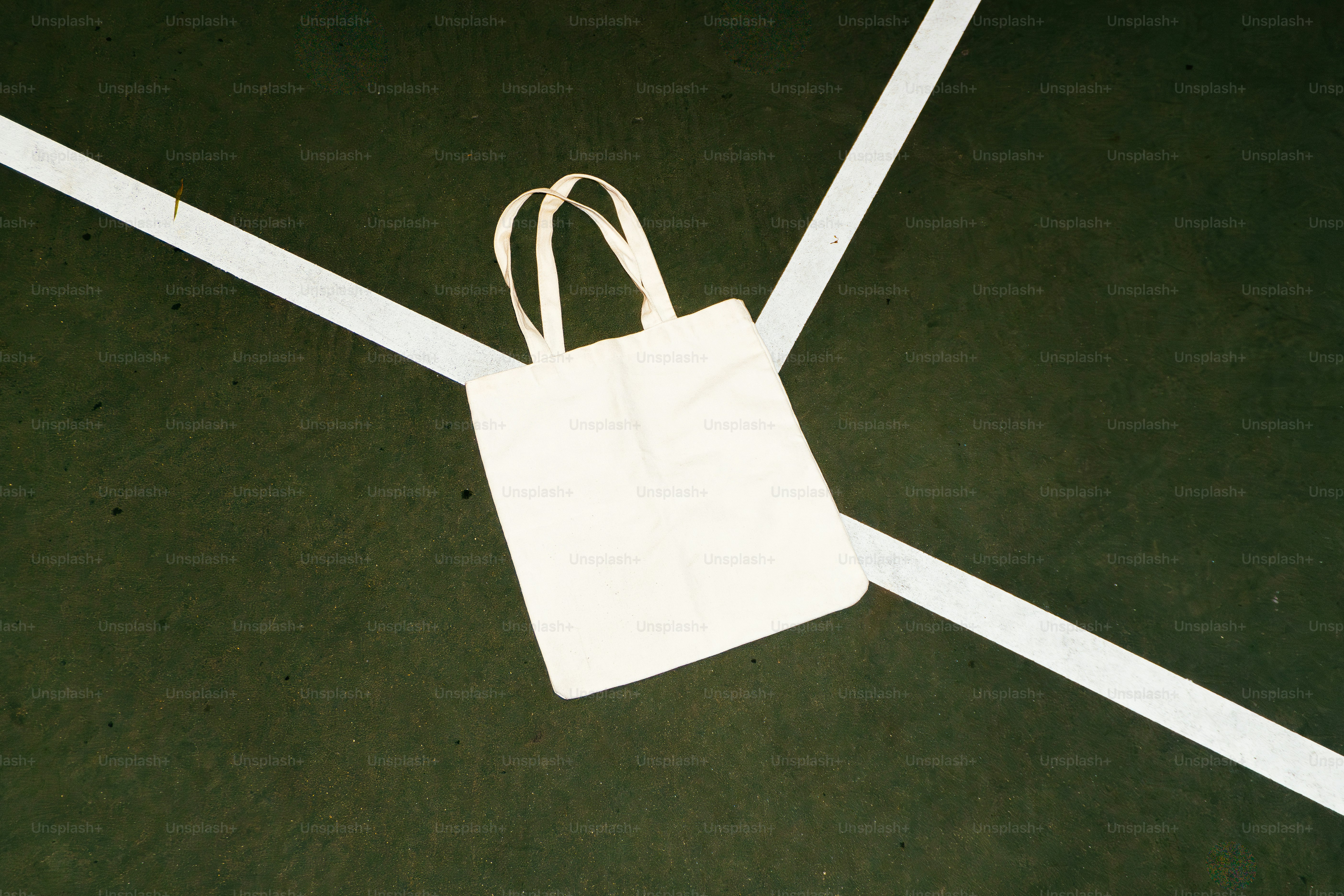 White tote bag resting on green surface with white lines