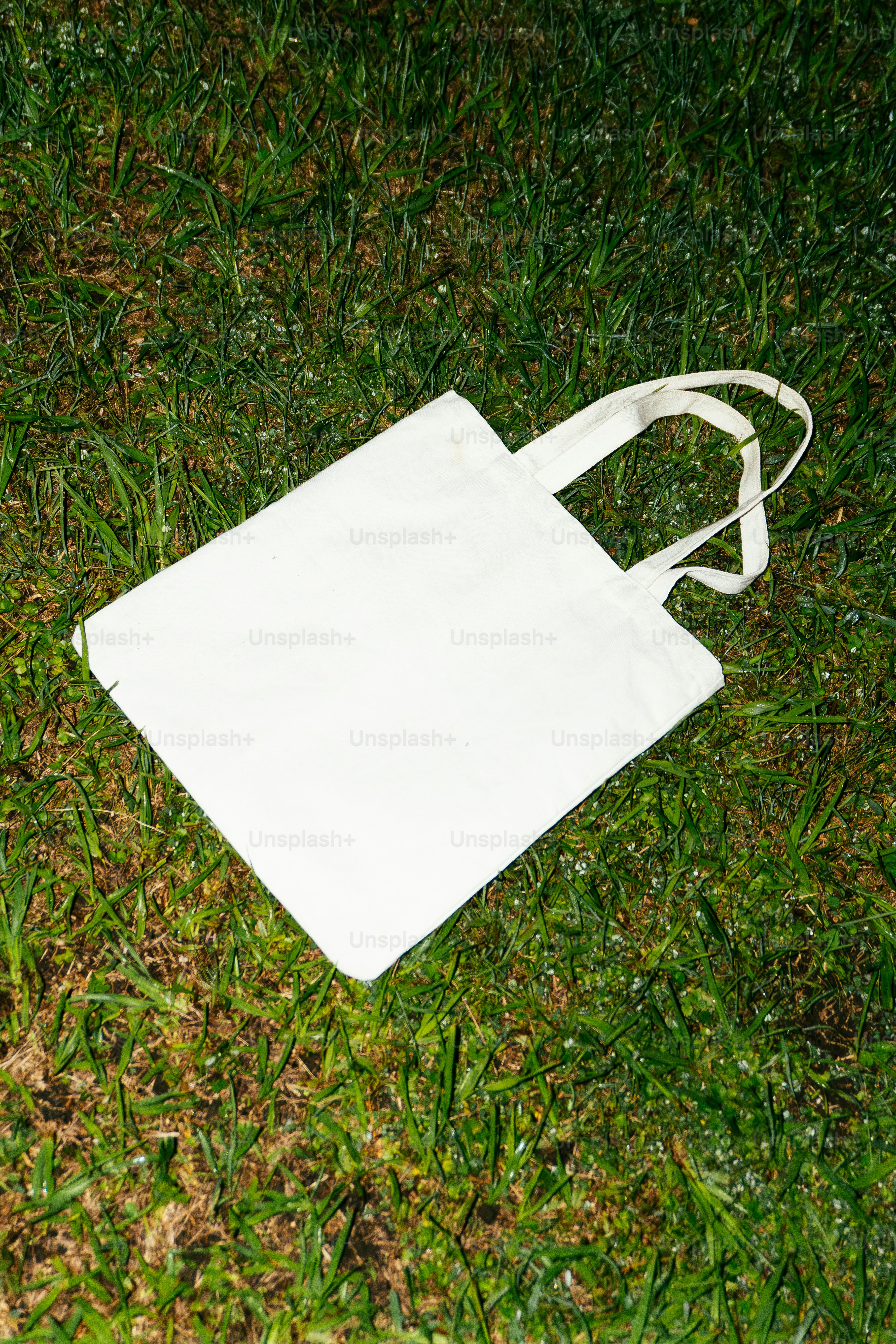 A white tote bag rests on green grass.