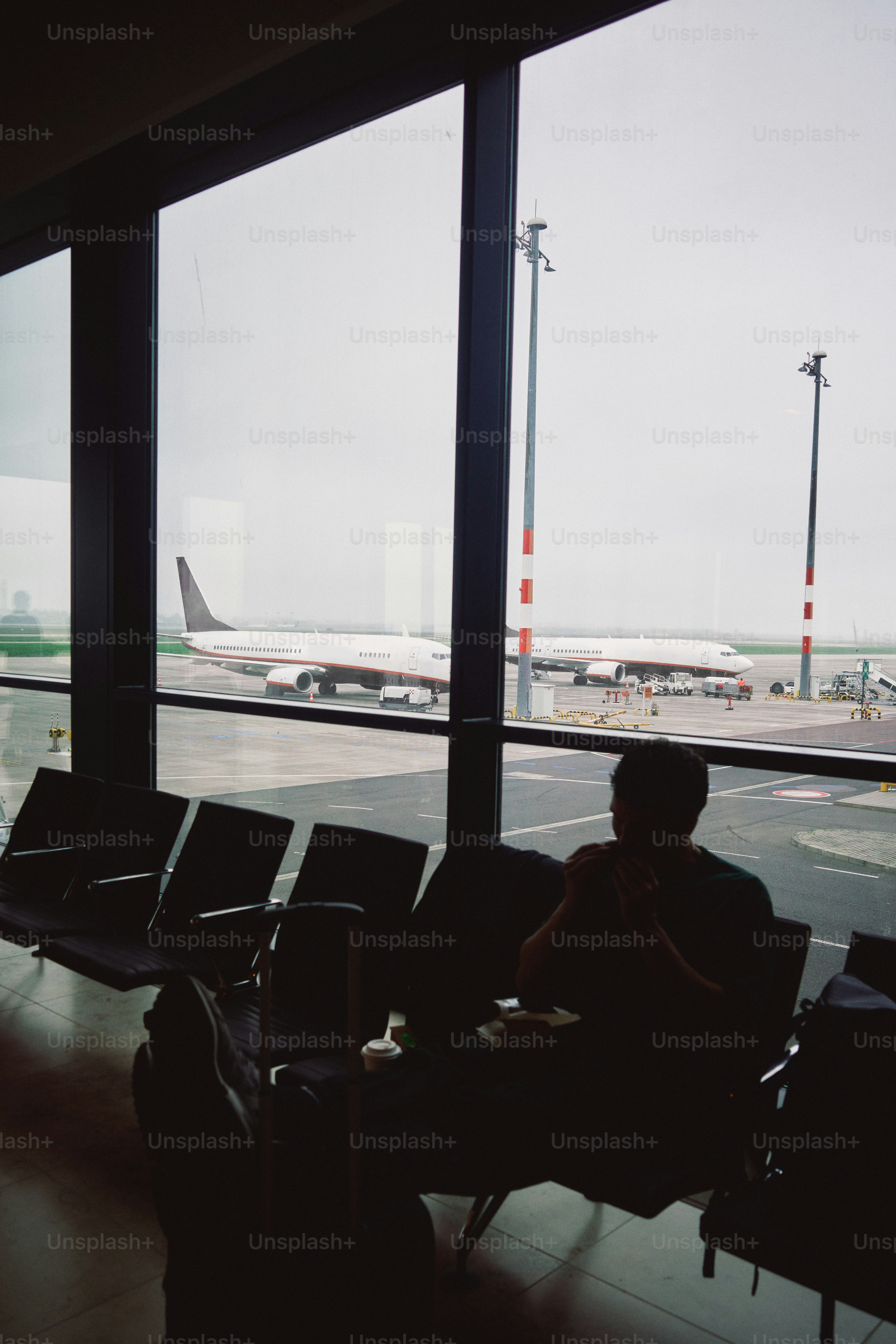 Man sits in airport waiting area with airplane outside