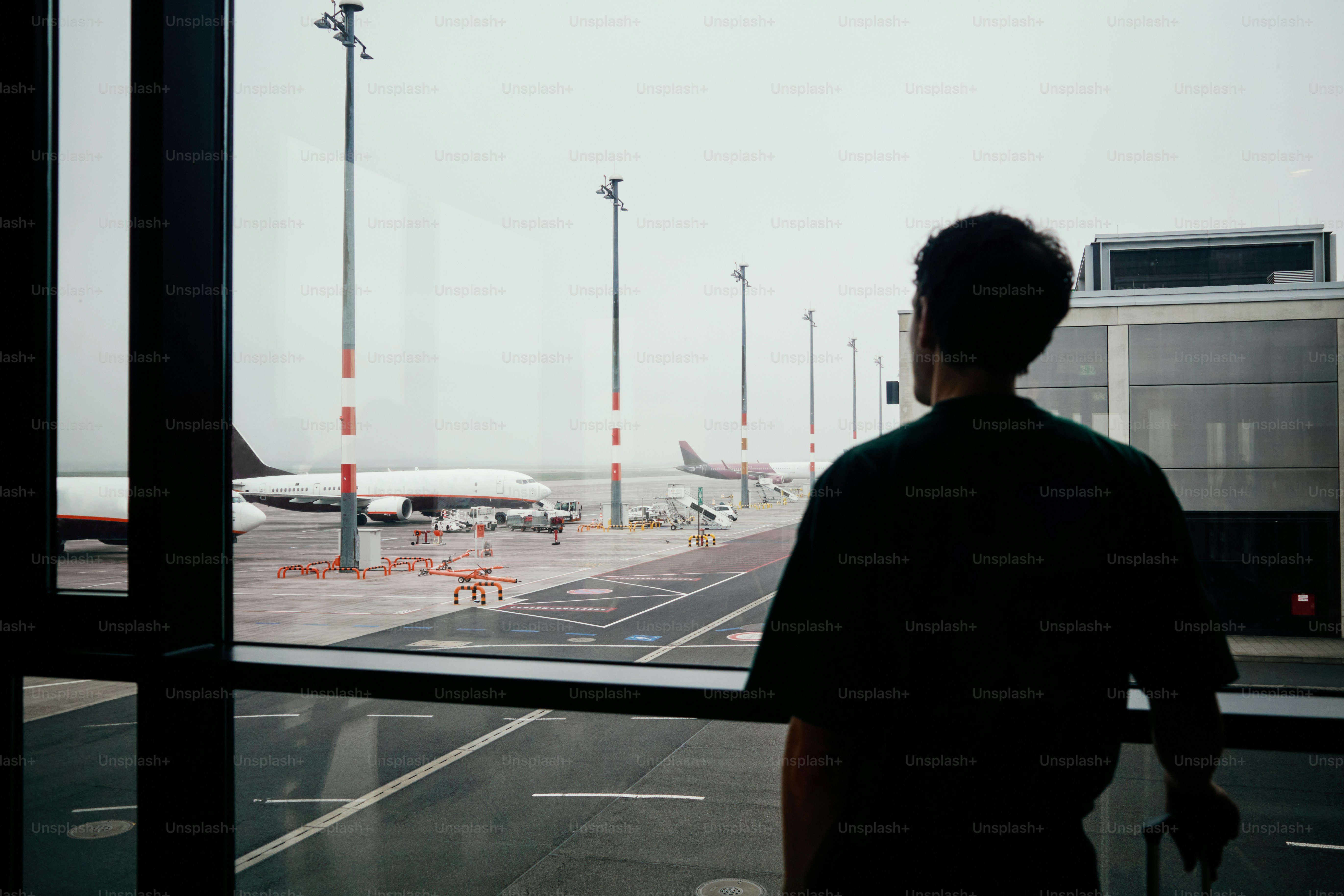 Man looking at airplanes through airport window