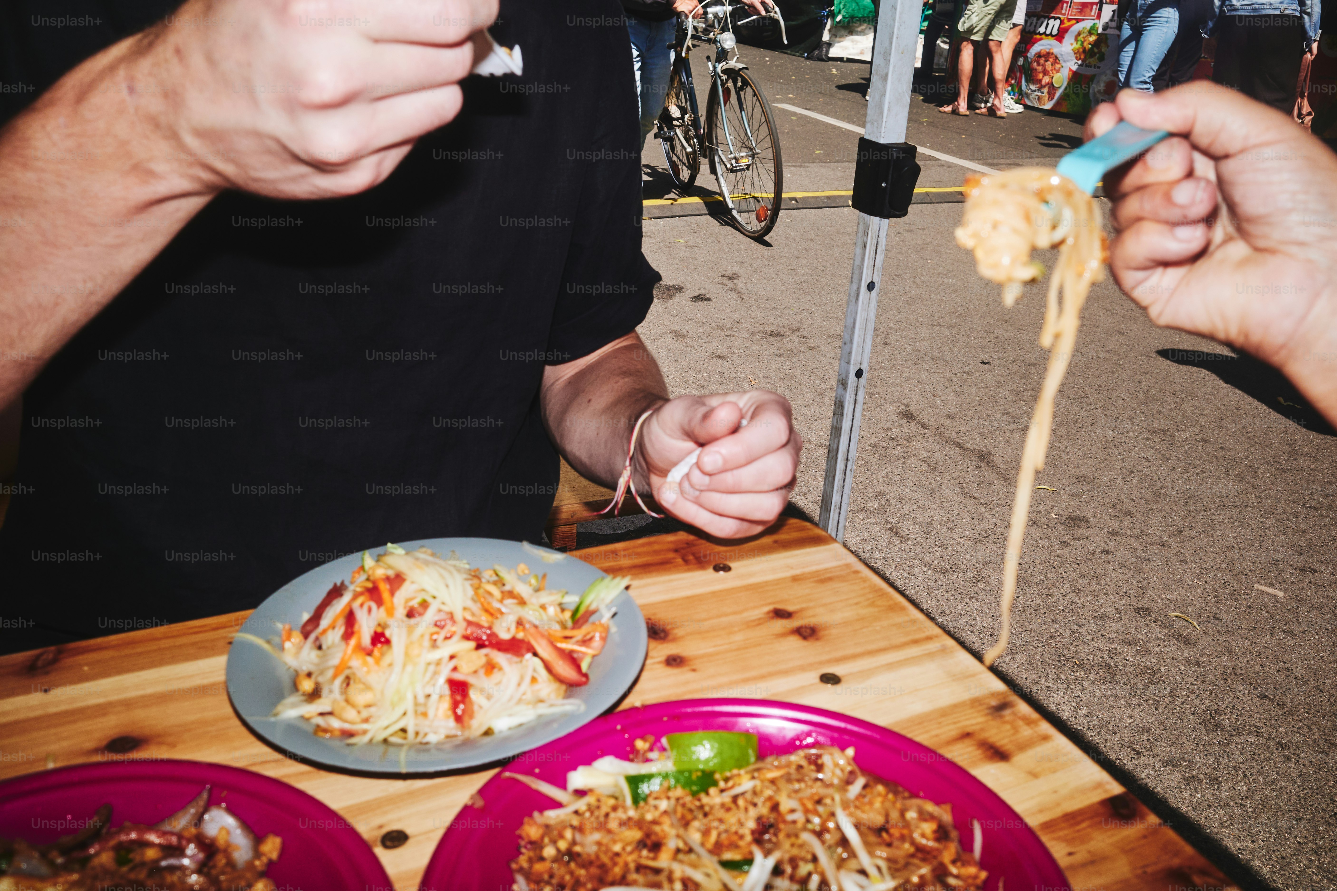 People eating noodles and salad at an outdoor table