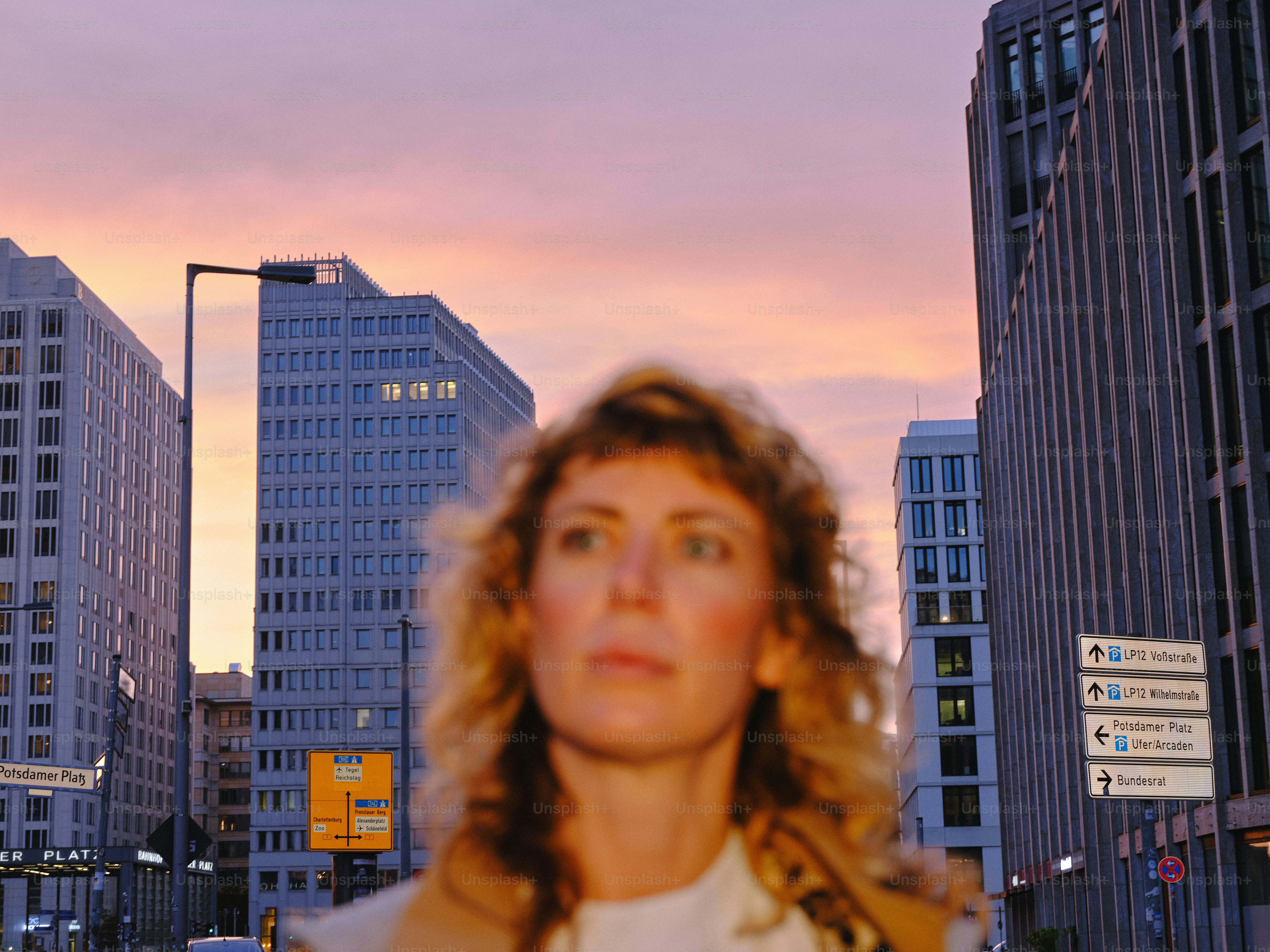 Woman in city street with buildings at sunset