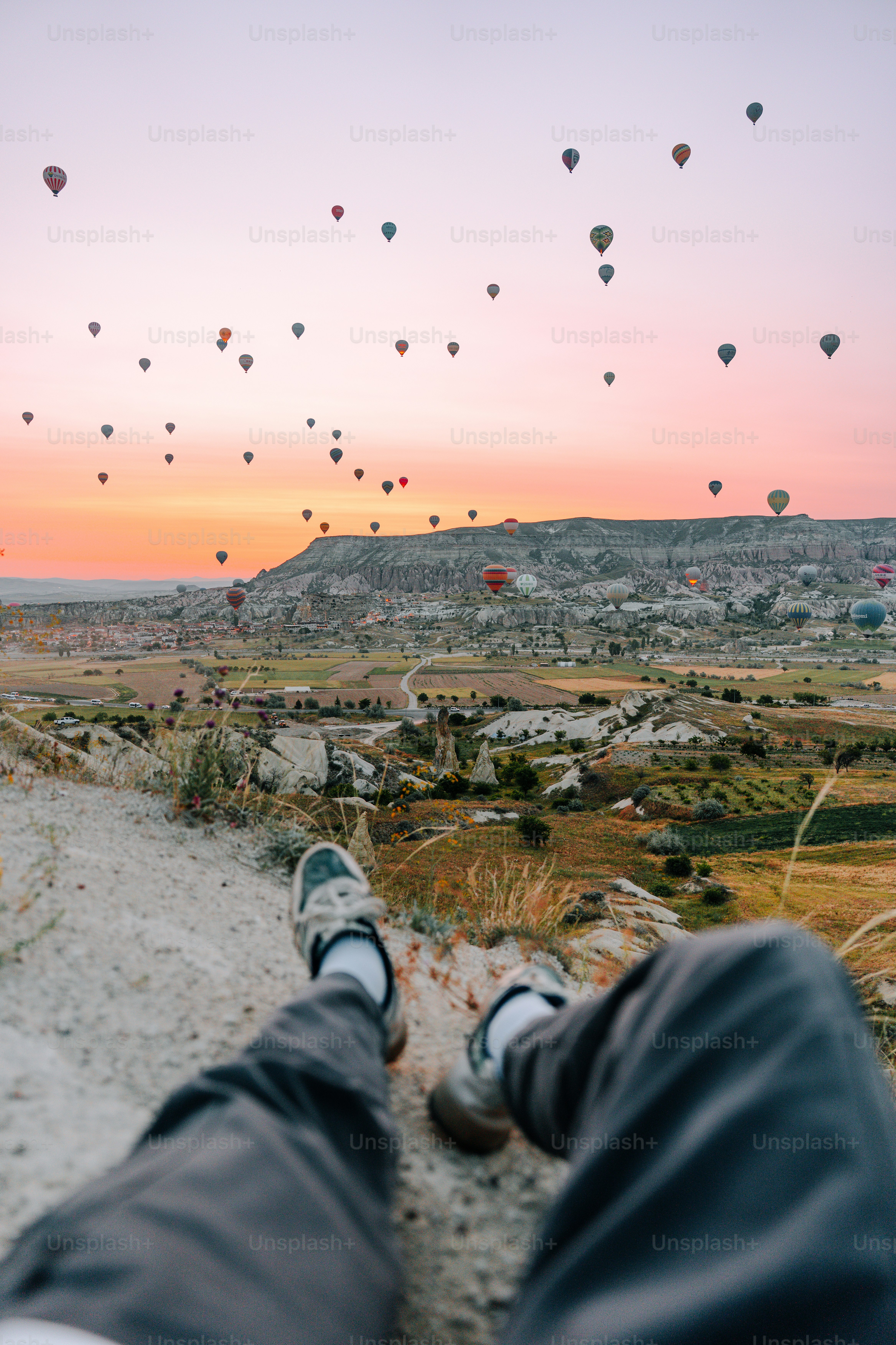 Hot air balloons float over a scenic landscape at sunrise
