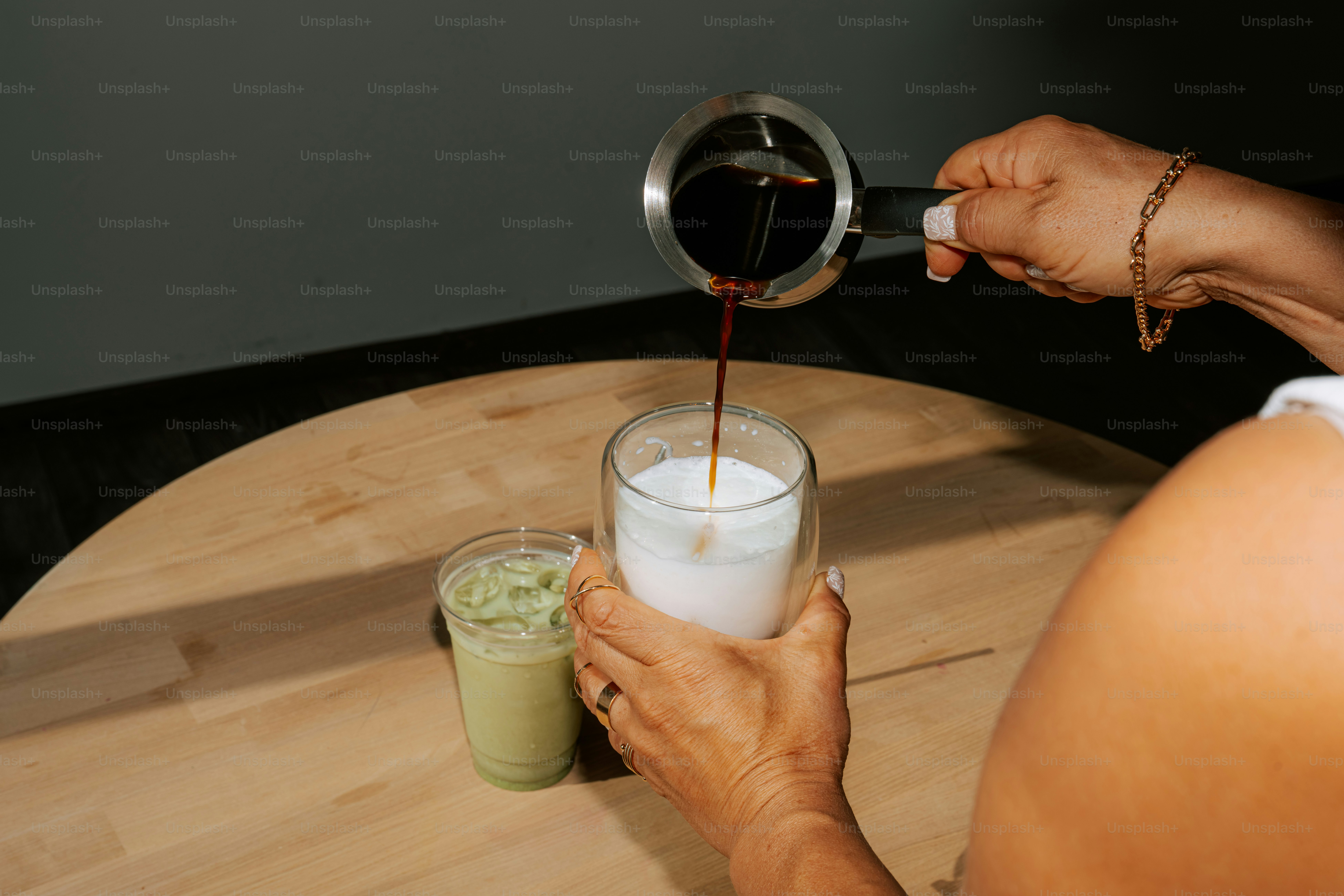 Pouring coffee into a glass with milk.
