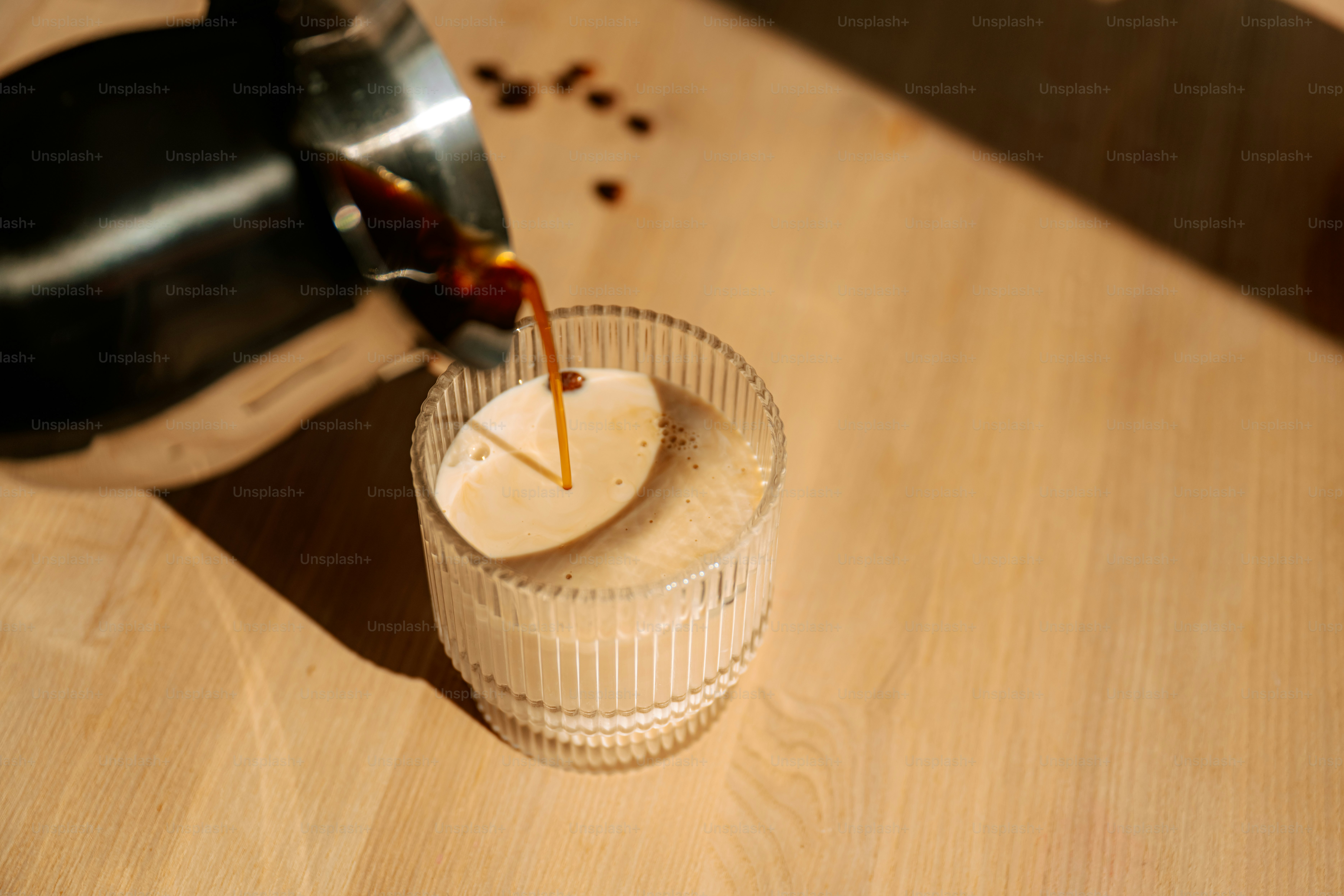 Coffee being poured into a glass with foam.