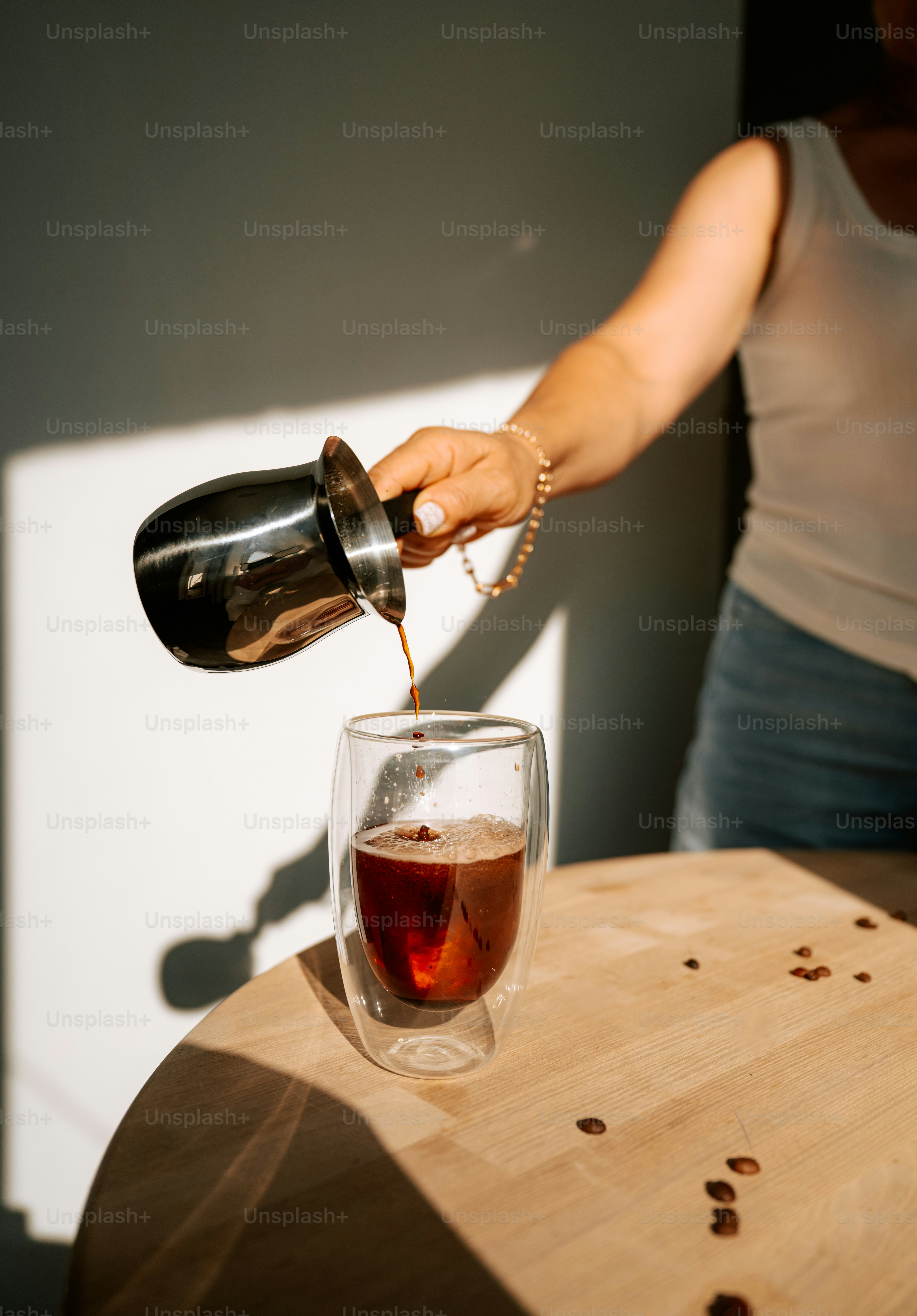 Pouring coffee into a double-walled glass mug.