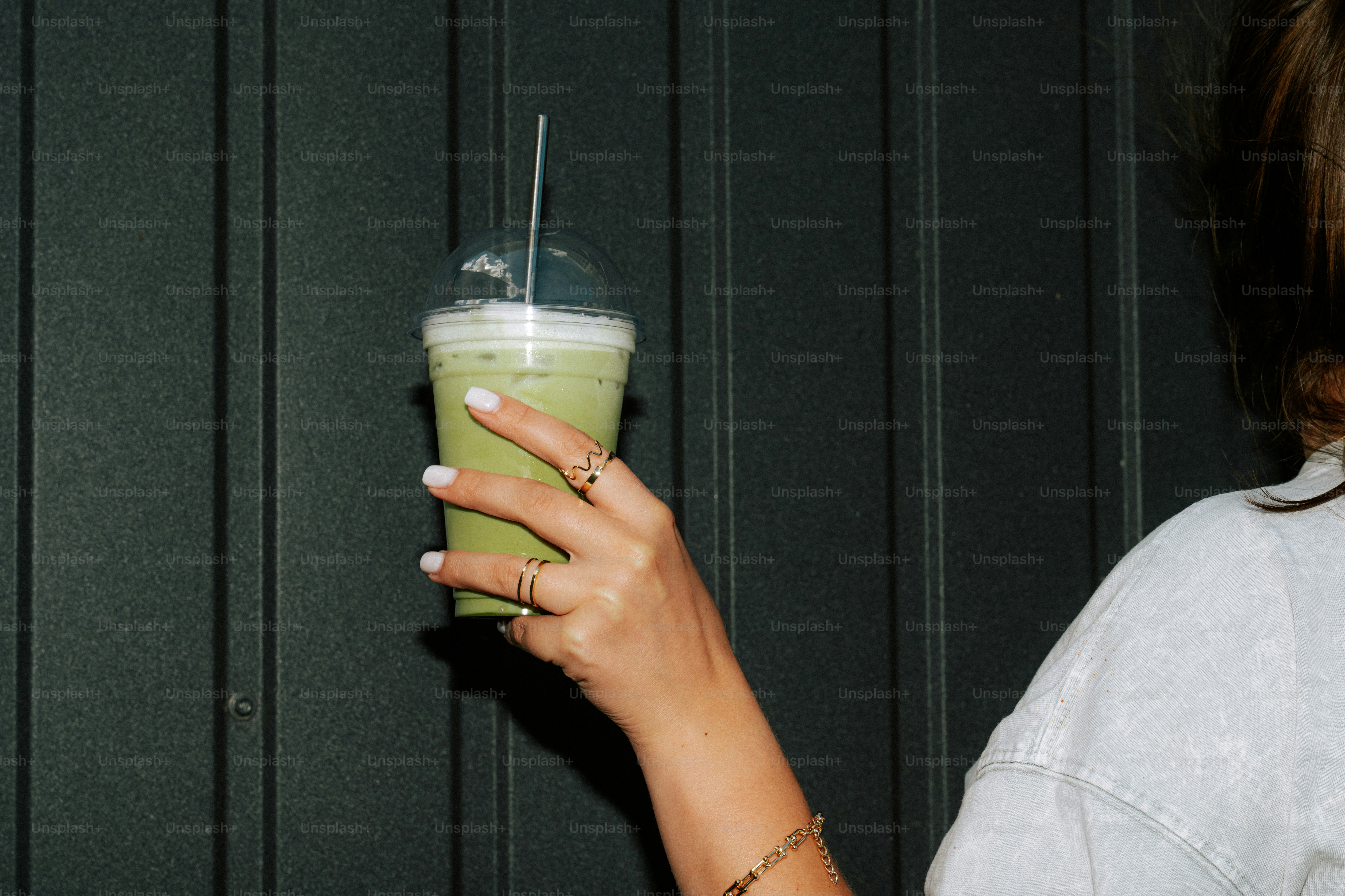 Woman holding a green iced drink with a straw