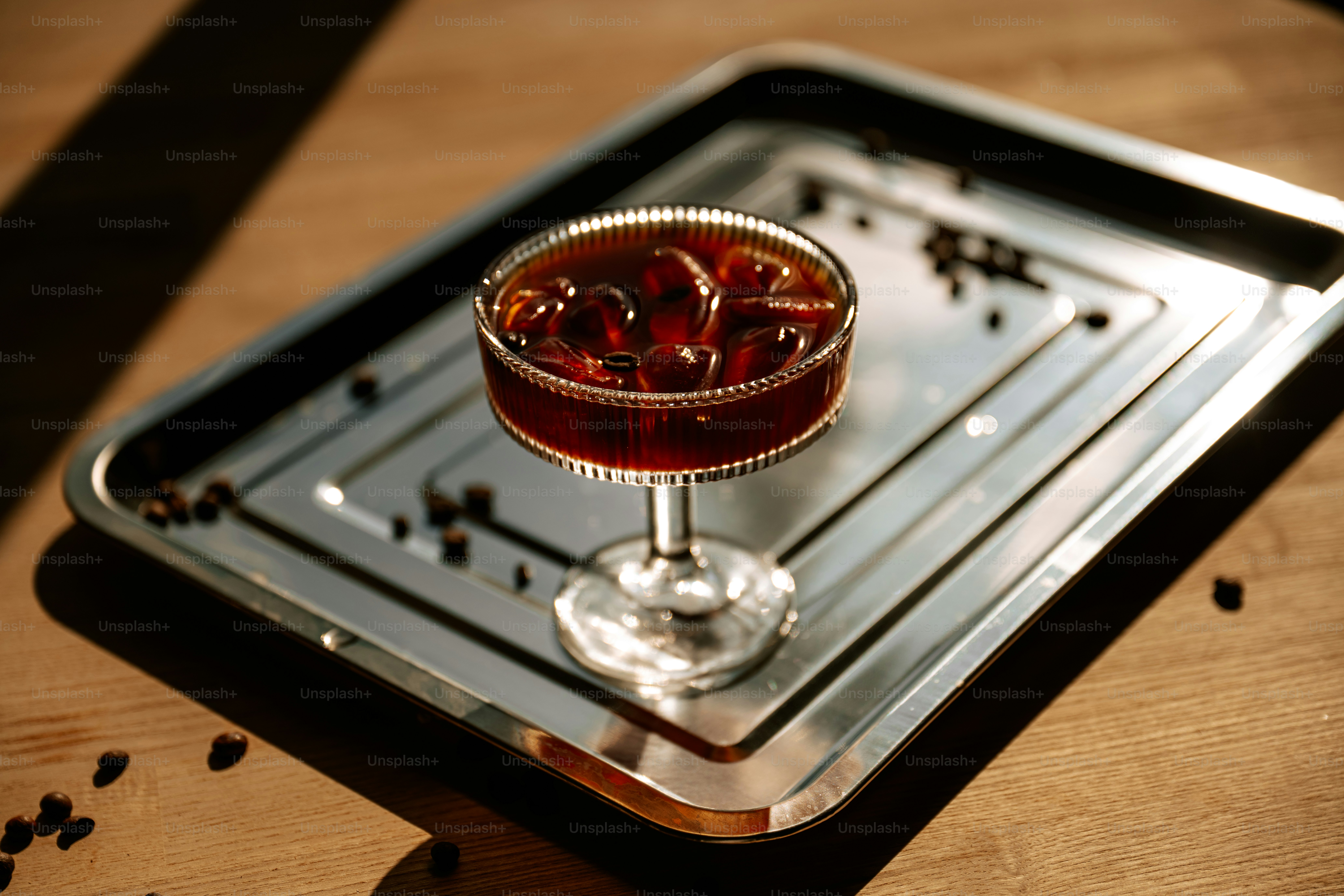 A glass of iced coffee with ice on a tray