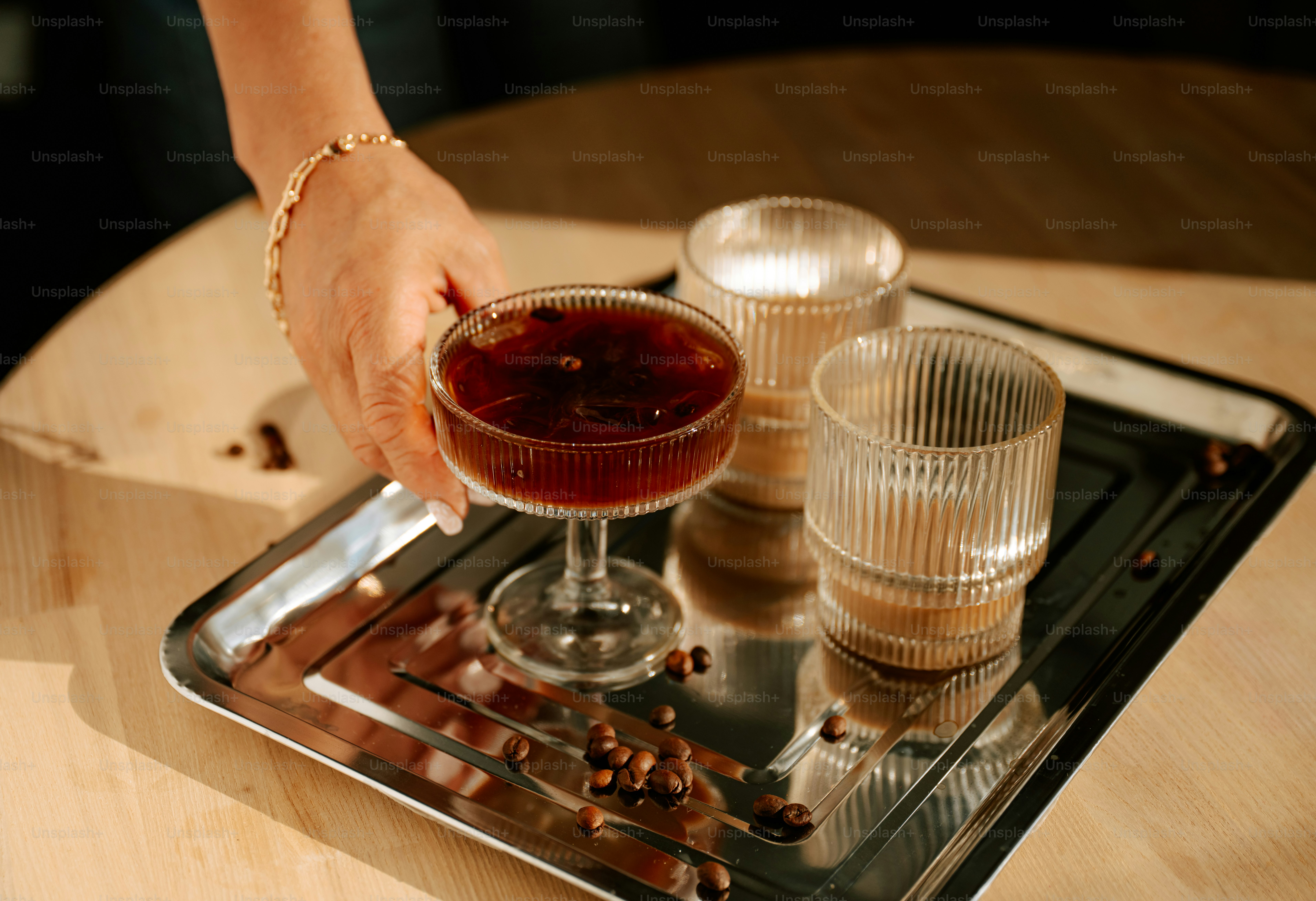 Hand reaching for a dark cocktail on a tray