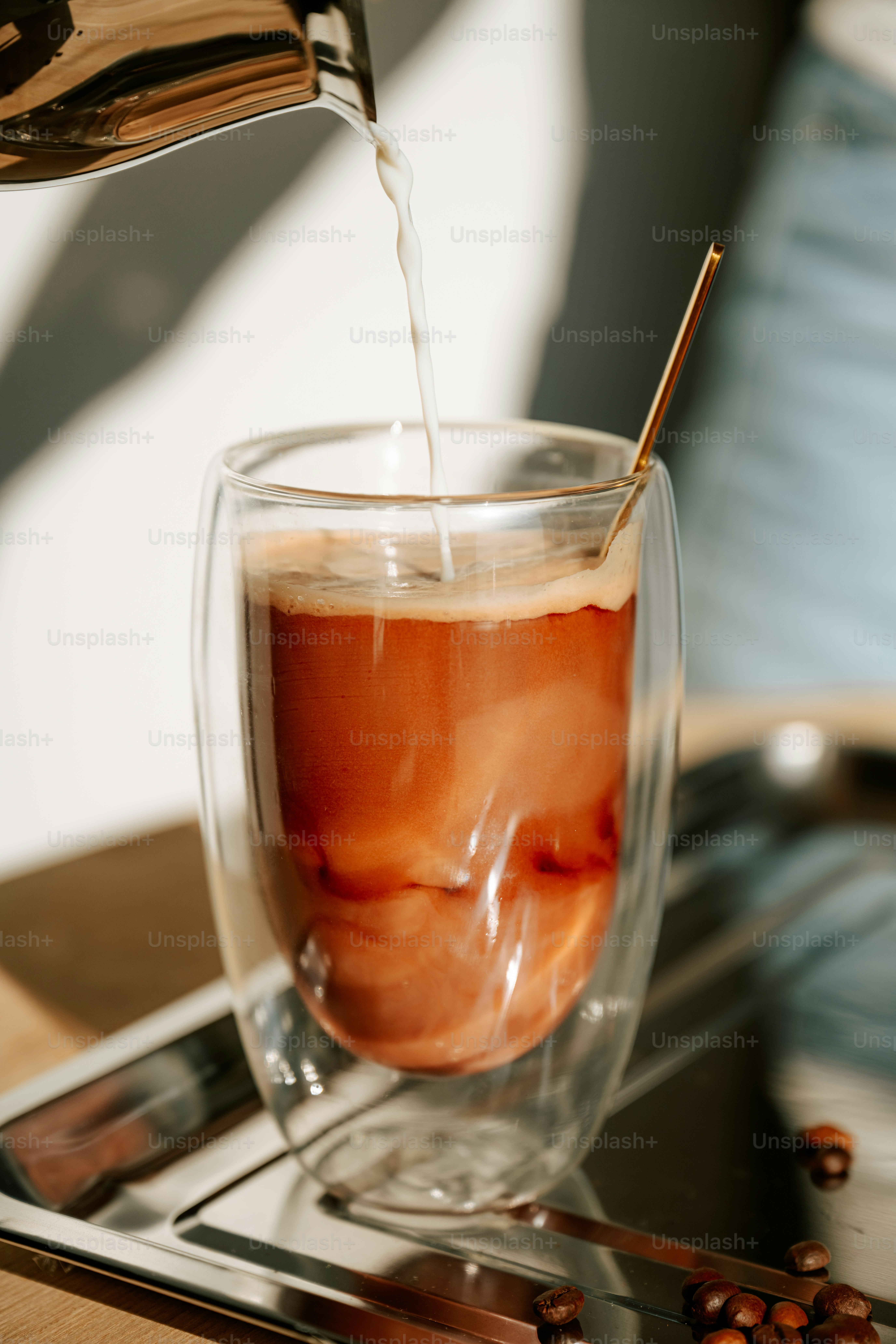 Pouring cream into coffee in a double-walled glass