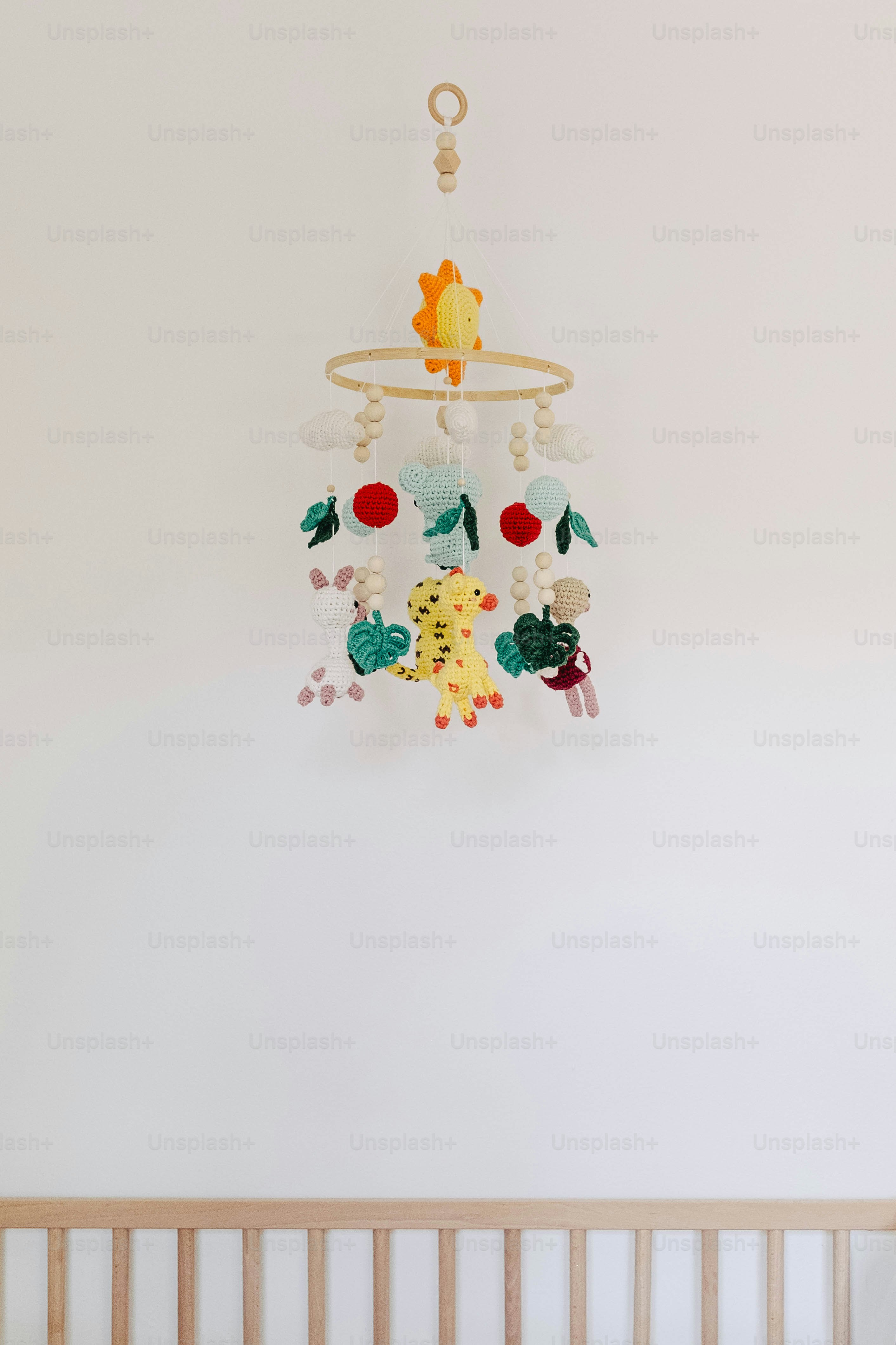 A colorful baby mobile with animal and fruit shapes.